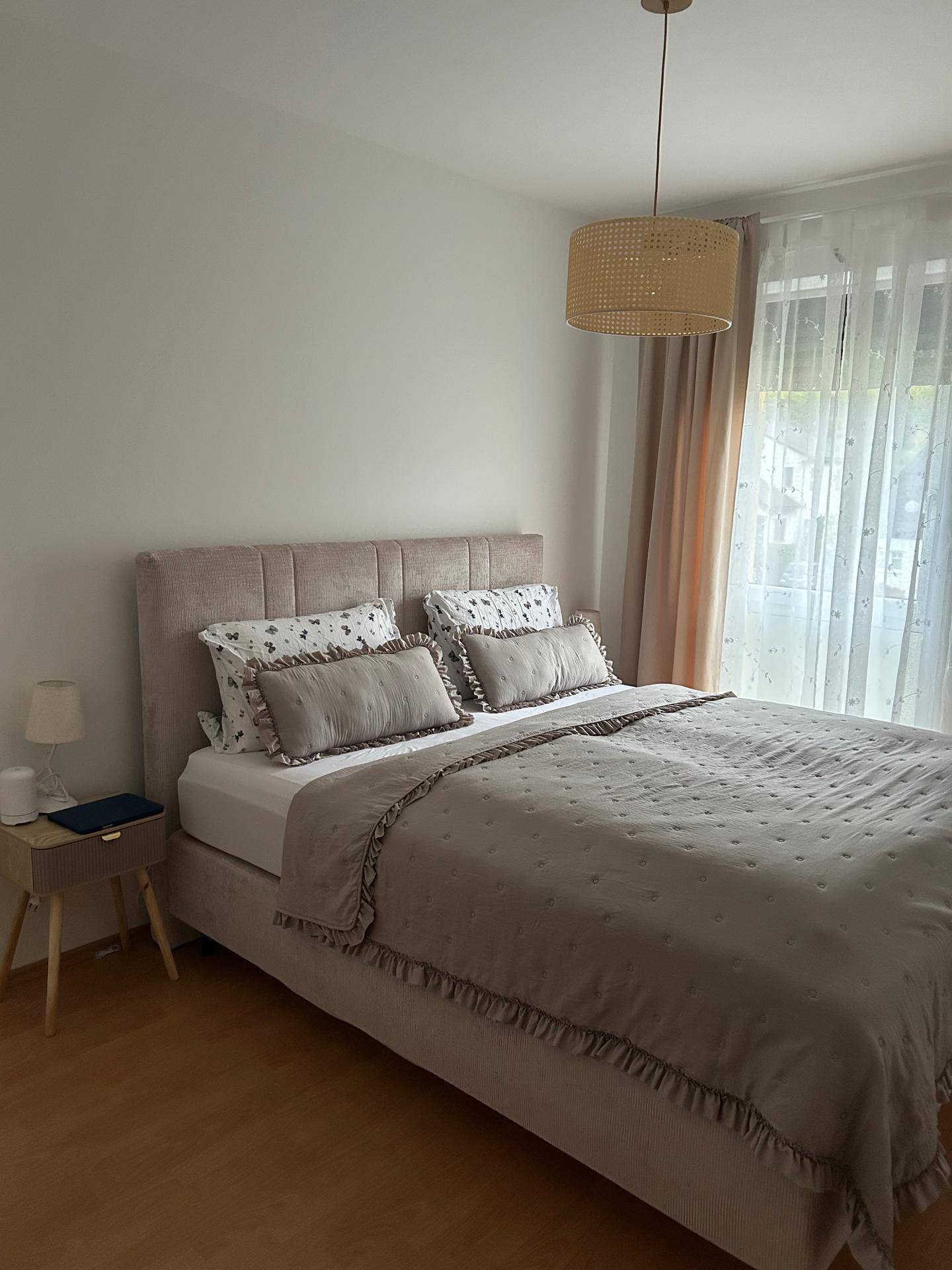 Gemütliches Schlafzimmer mit Doppelbett, Holzboden und Vorhängen für Privatsphäre.
