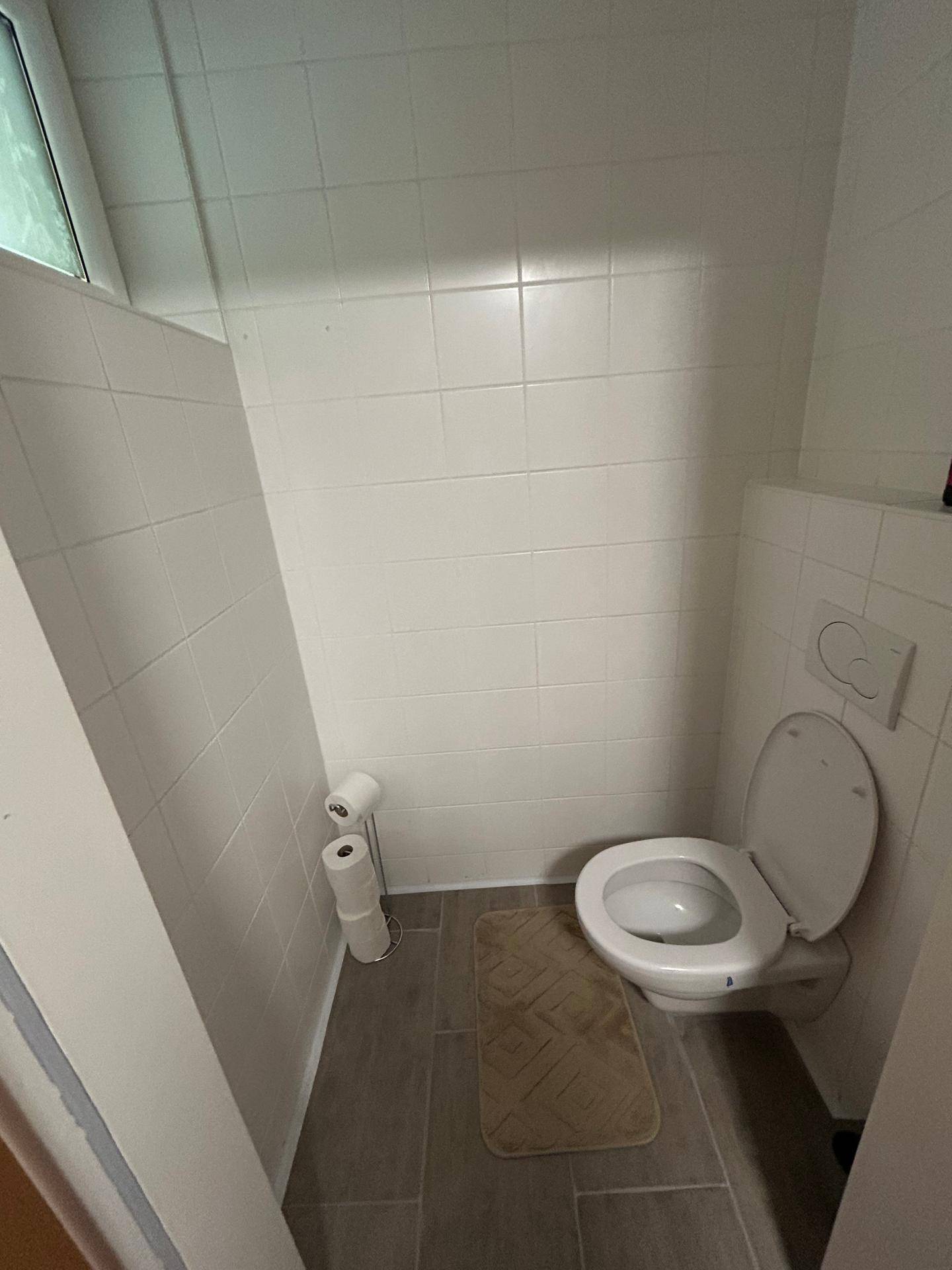 Kleines Gäste-WC mit Wand-WC und Fliesenboden.