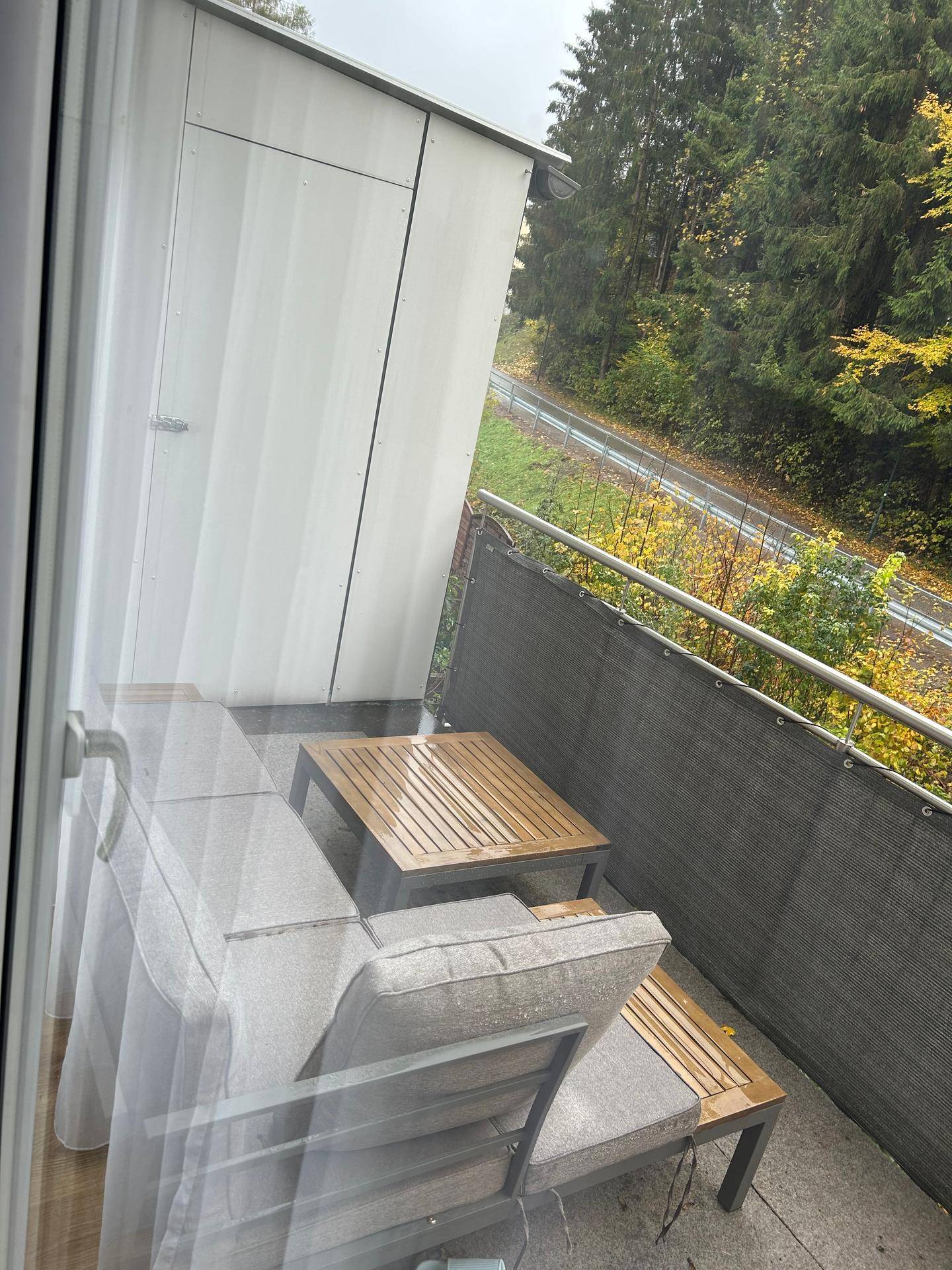 Gemütlicher Balkon mit Sitzgelegenheiten und einem ruhigen Blick ins Grüne und auf Bahngleise.