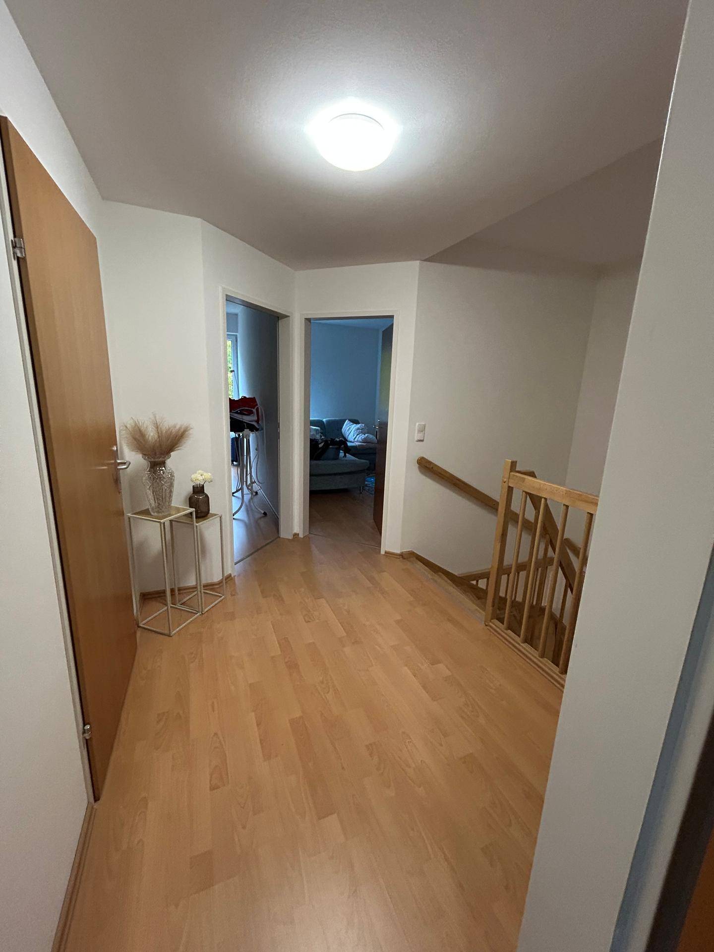 Geräumiger Flur mit Holzboden, Treppenaufgang und Zugang zu verschiedenen Zimmern.