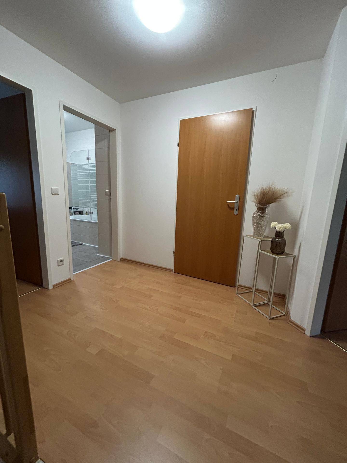 Heller Flur mit Holzboden und Zugang zu weiteren Räumen.
