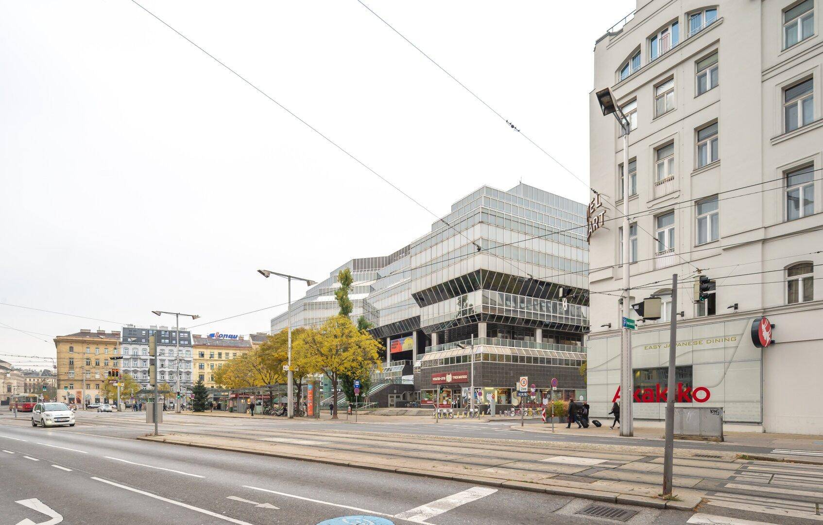 Weitläufige Stadtansicht mit modernen und klassischen Gebäuden, Straßenbahnschienen und Verkehr.