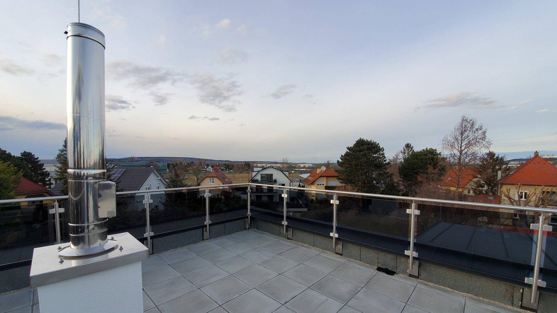 Weitläufige Dachterrasse mit Panoramablick über die Dächer und die umliegende Landschaft.
