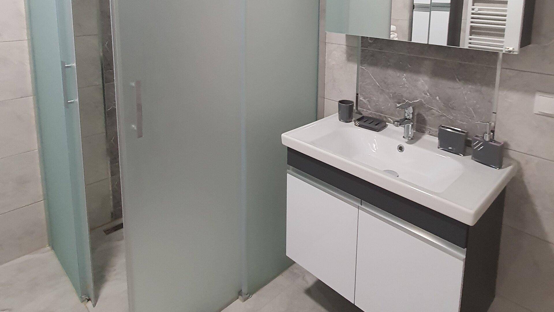 Modernes Badezimmer mit begehbarer Dusche und stilvollem Waschtisch mit Unterschrank.