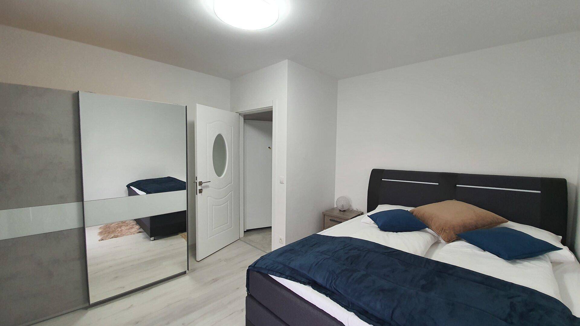 Helles Schlafzimmer mit großem Bett und einem geräumigen Spiegelschrank.