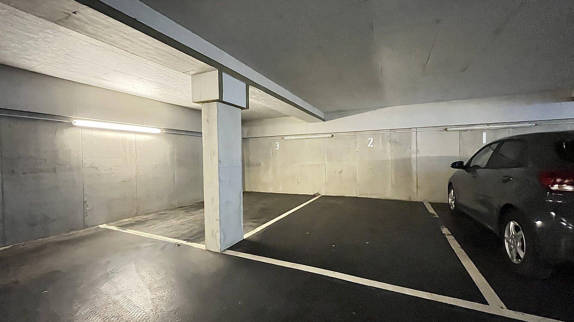 Tiefgarage mit markierten Stellplätzen und Betonwänden.