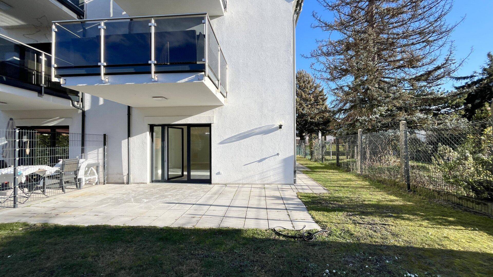 Außenbereich mit gepflasterter Terrasse und Rasenfläche neben dem Gebäude.