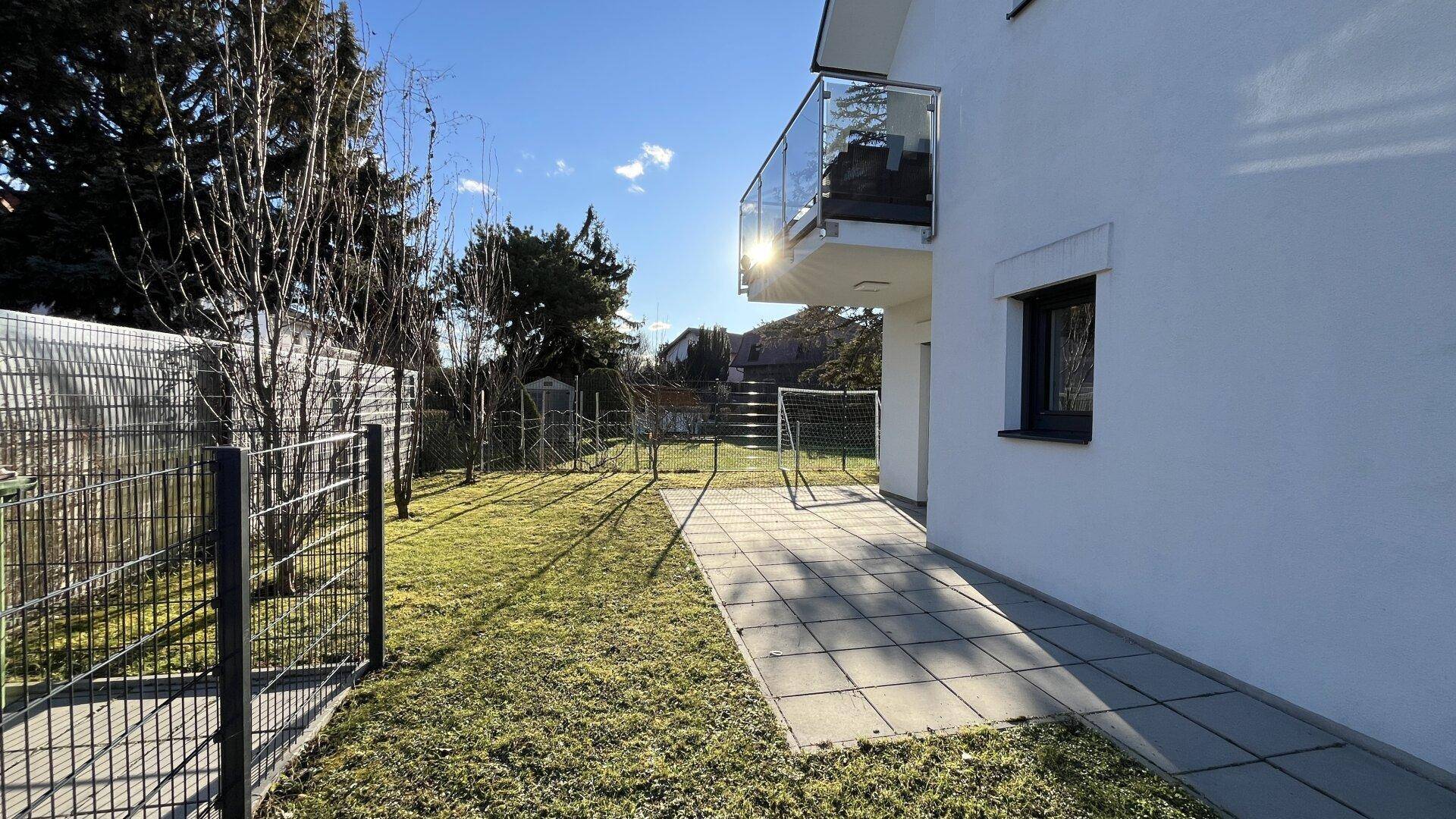 Seitlicher Gartenbereich mit gepflastertem Weg und Blick auf das Gebäude.