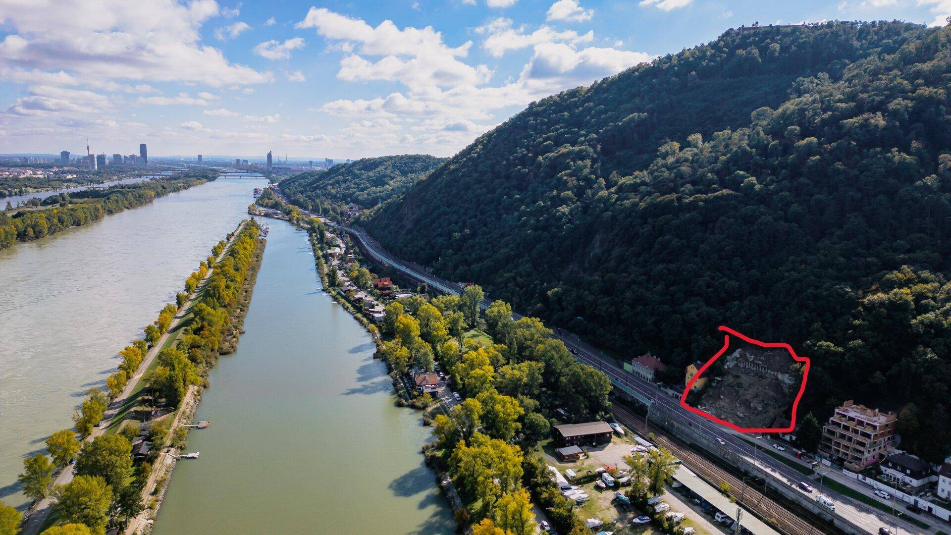 Luftaufnahme der Donau und des bewaldeten Berges mit einer markierten Fläche am Hang.