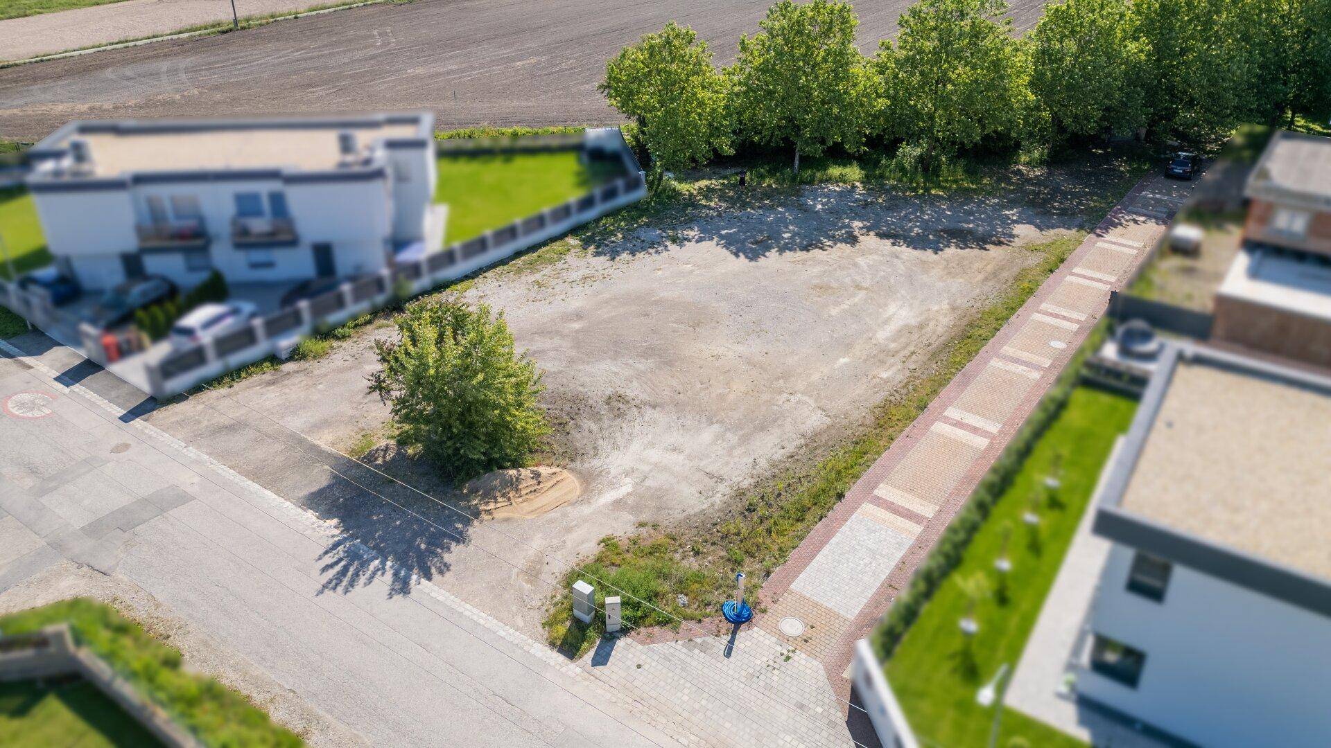 Luftaufnahme eines unbebauten Grundstücks mit angrenzenden Häusern und Feldern in ländlicher Umgebung.