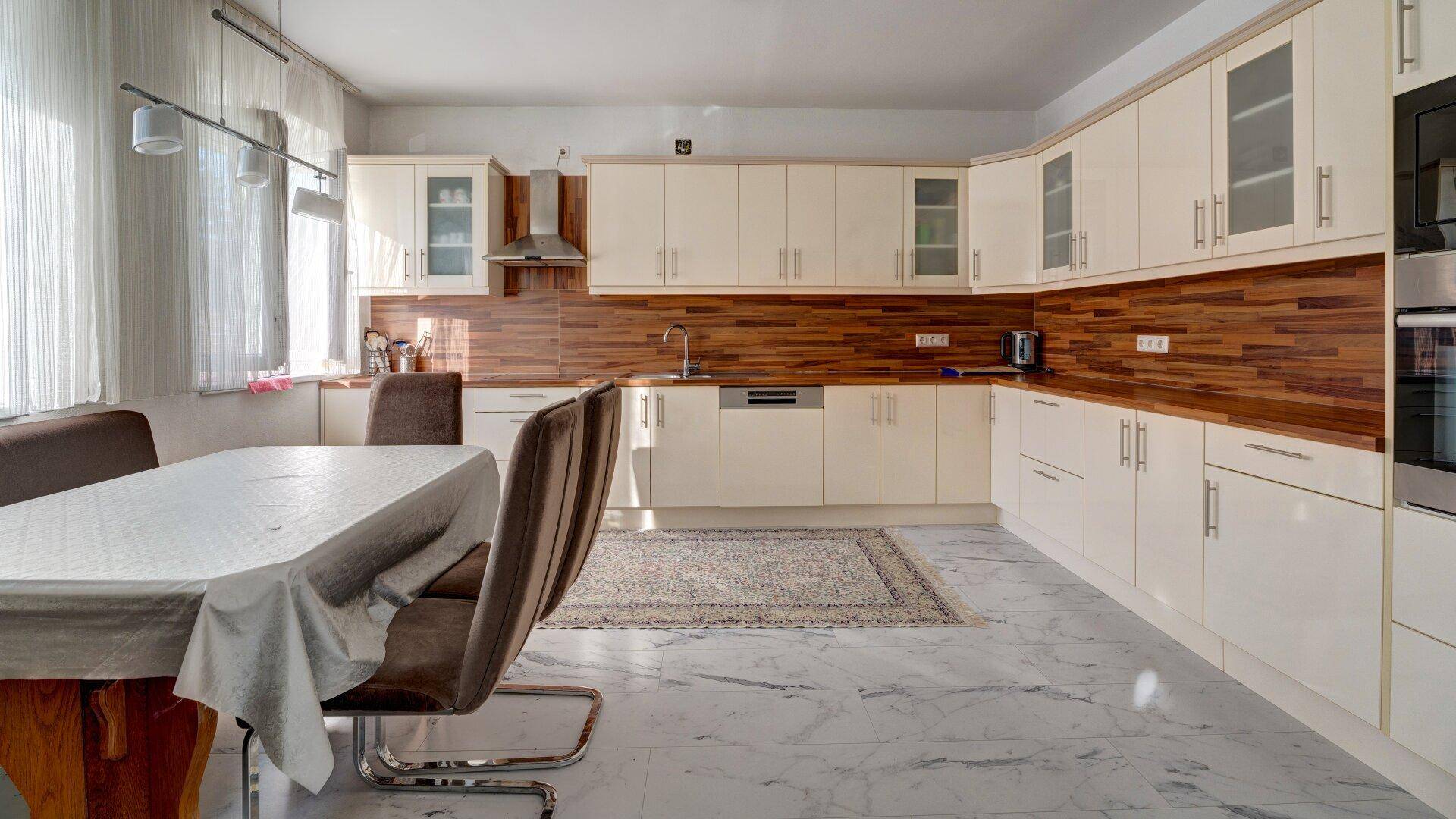 Geräumige Küche mit cremefarbenen Einbauschränken, Holzdetails und einem Essbereich.