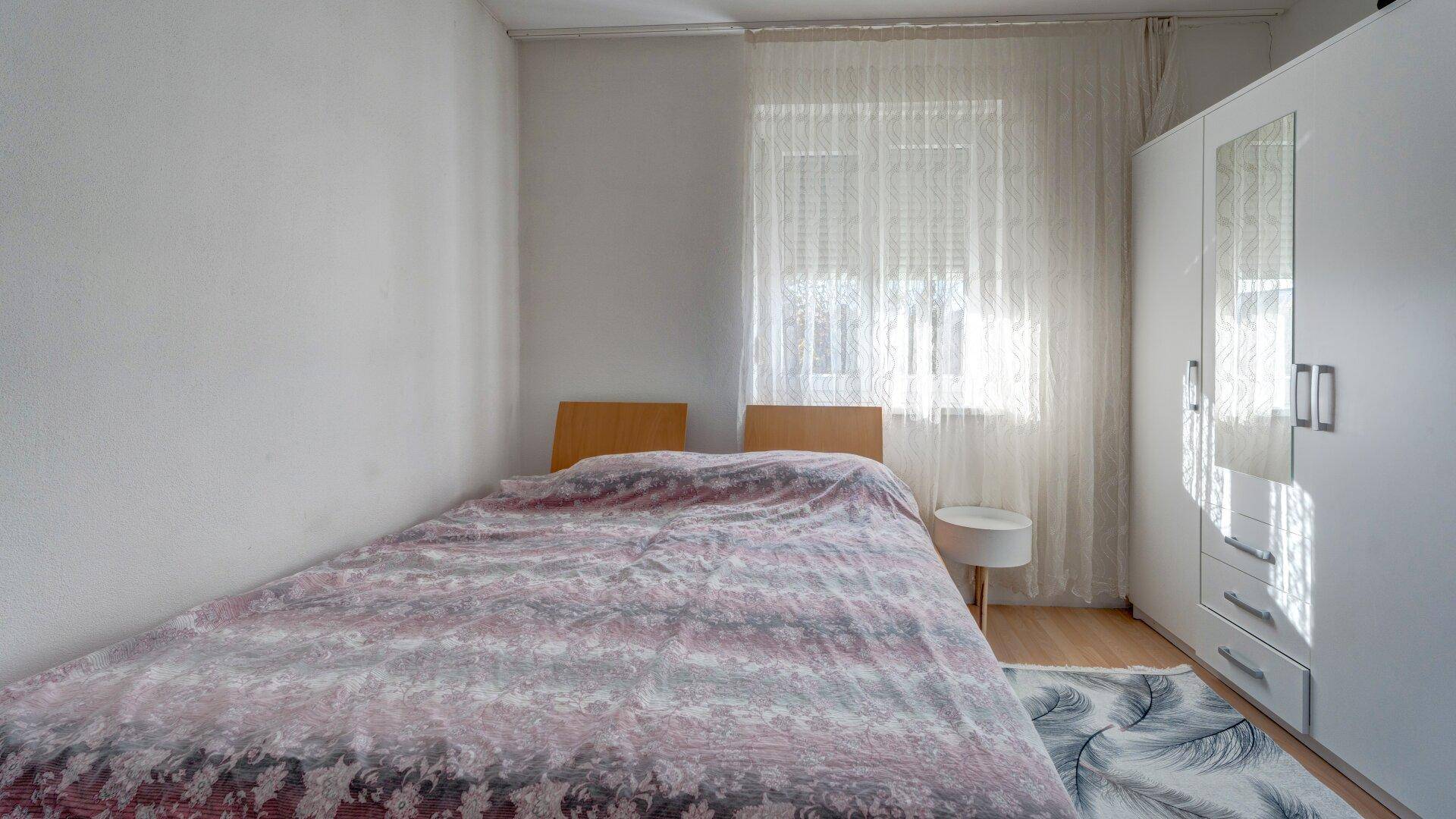 Helles Schlafzimmer mit Doppelbett und weißem Kleiderschrank, ideal für erholsame Nächte.