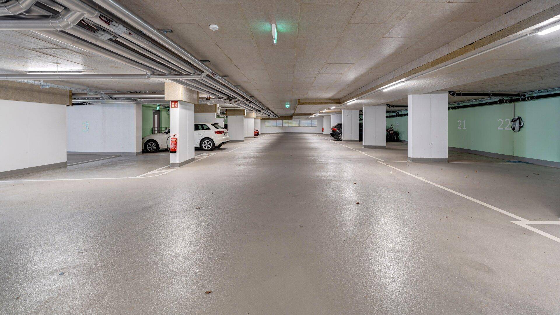 Geräumige Tiefgarage mit sauberem Betonboden und klar markierten Stellplätzen für Fahrzeuge.