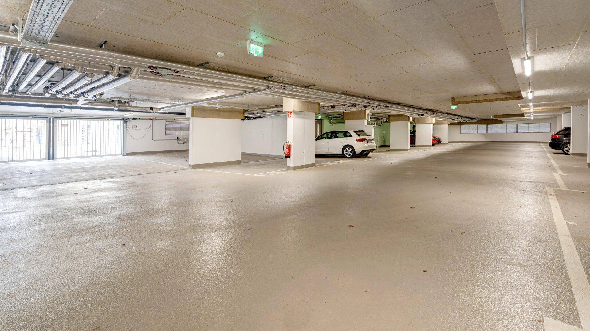 Weitläufige Tiefgarage mit markierten Stellplätzen und Zufahrtstoren.