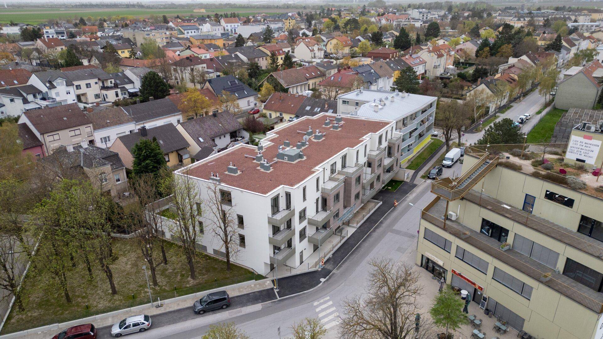 Luftaufnahme einer neuen Wohnanlage in einer städtischen Umgebung mit umliegenden Häusern.