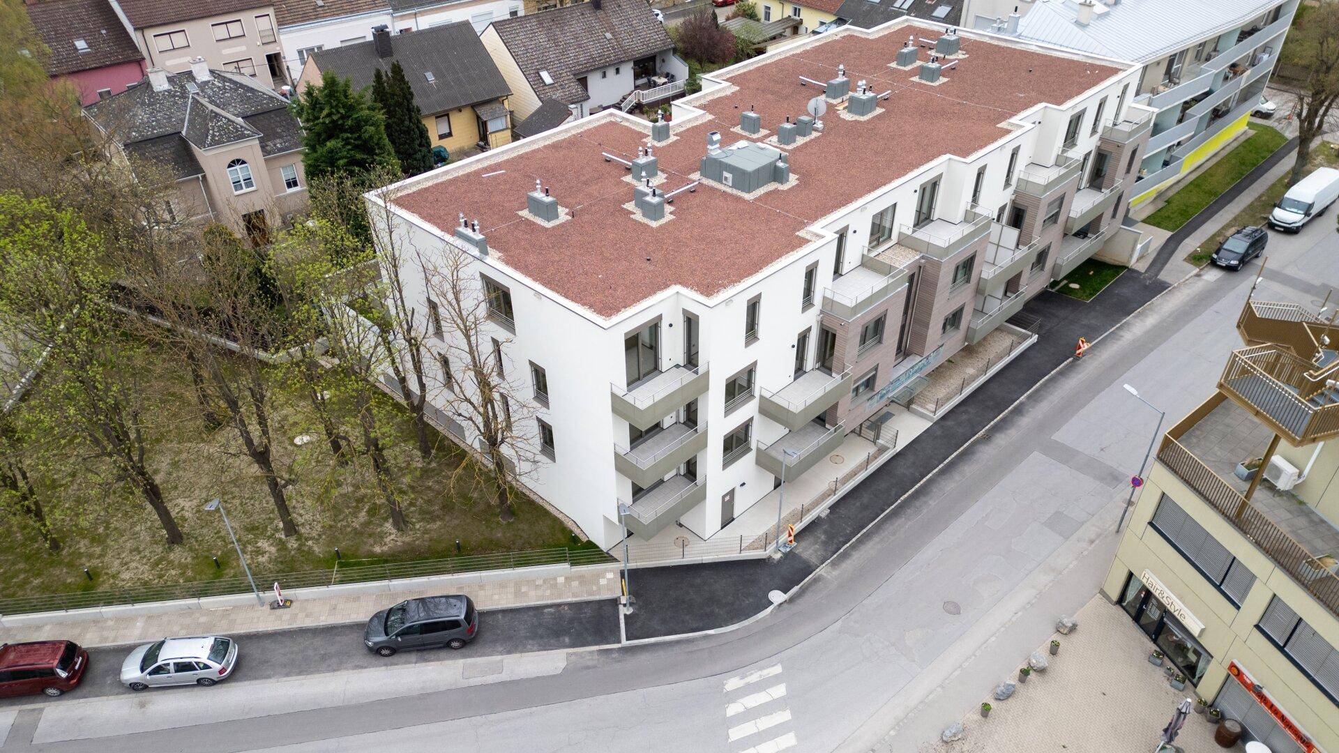Vogelperspektive auf eine moderne Wohnanlage mit Flachdach und umliegender Bebauung.