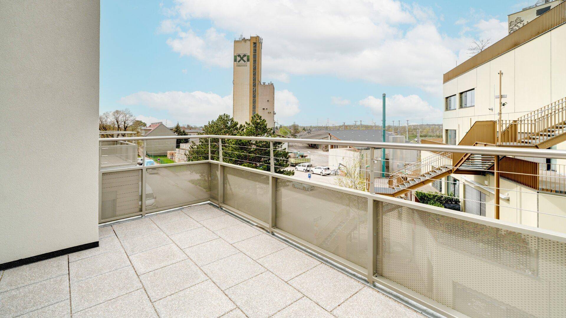 Geräumiger Balkon mit Fliesenboden und Metallgeländer, bietet einen weiten Blick auf die Umgebung.