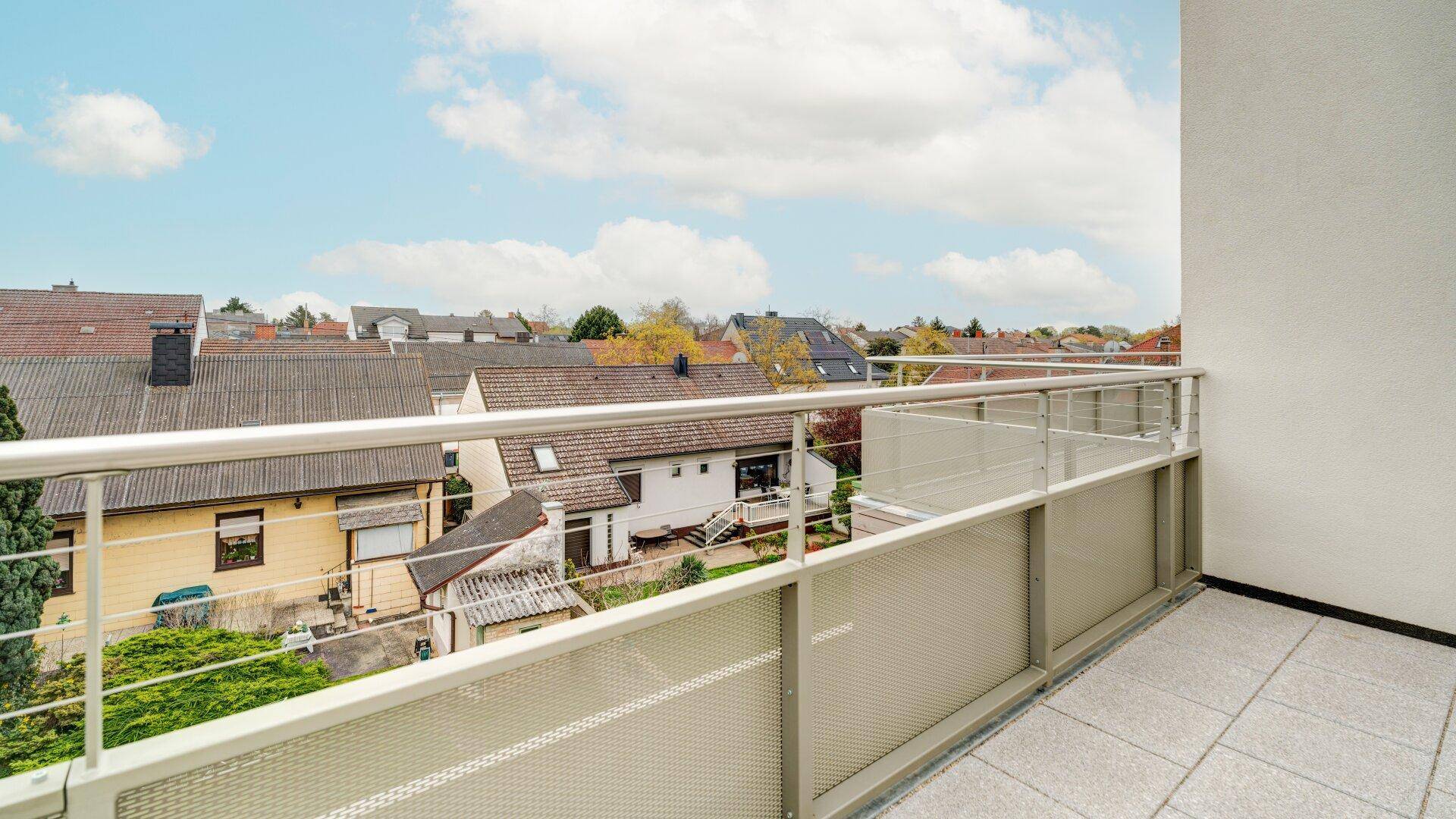 Heller Balkon mit Fliesenboden und Metallgeländer, bietet einen weiten Blick über die Dächer der Häuser.
