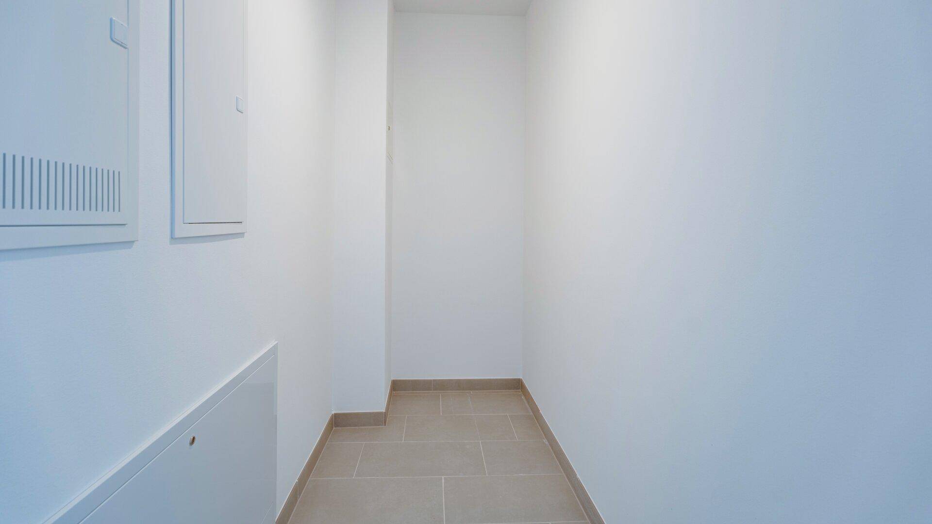 Kleiner Abstellraum oder Technikraum mit Fliesenboden und weißen Wänden.