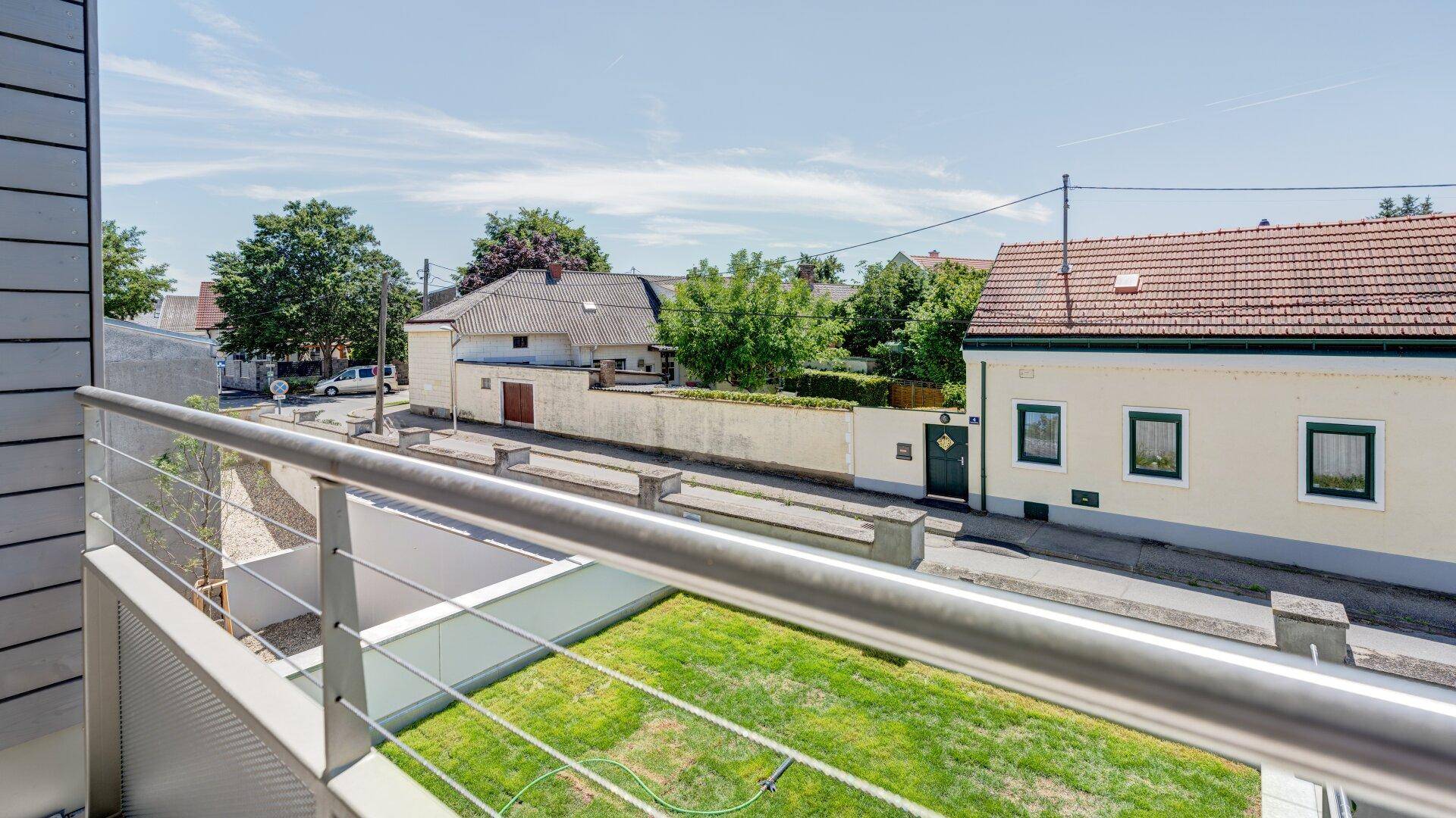 Geräumiger Balkon mit Blick auf eine grüne Fläche und die Nachbarschaft.