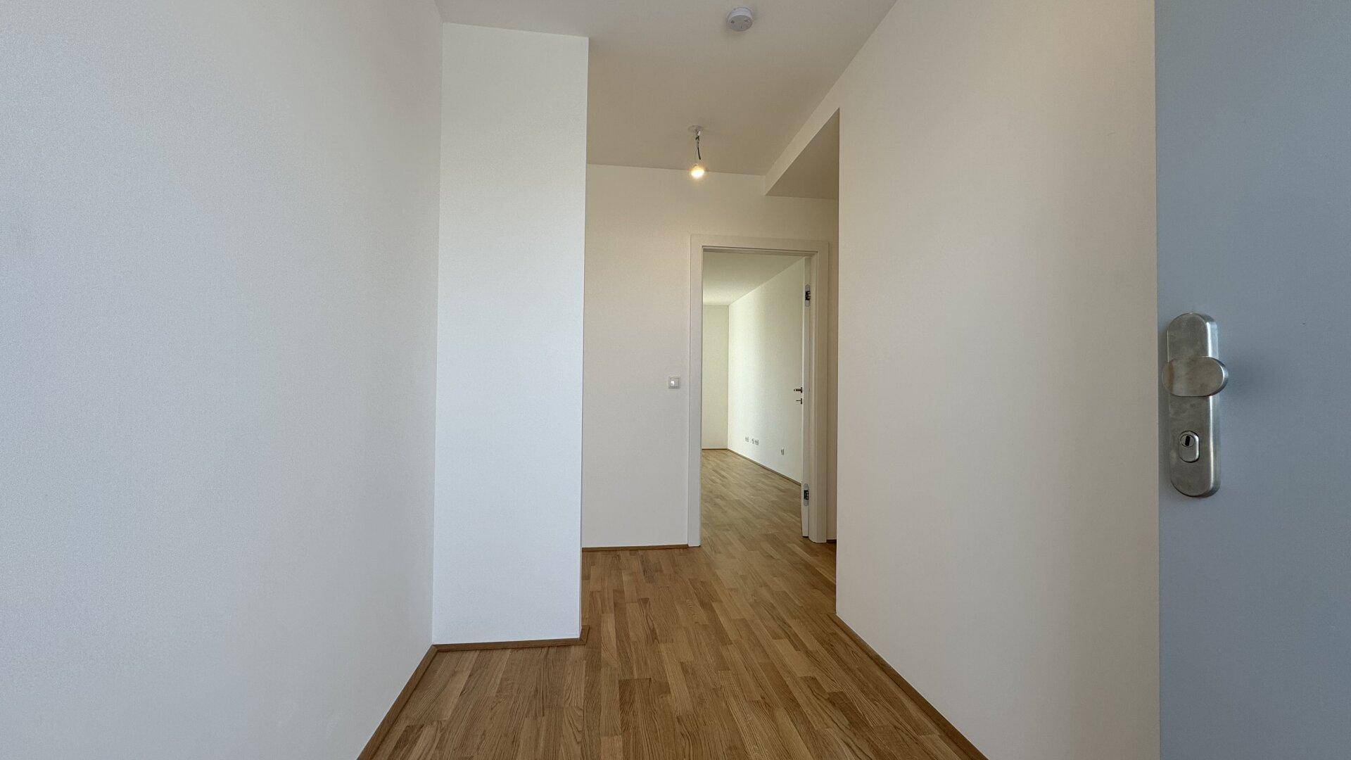 Heller Flur mit Holzparkettboden und Zugang zu weiteren Räumen.