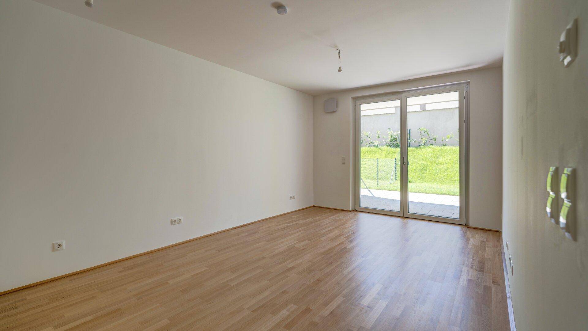 Lichtdurchfluteter Wohnbereich mit Holzboden und großen Schiebetüren zum Außenbereich.