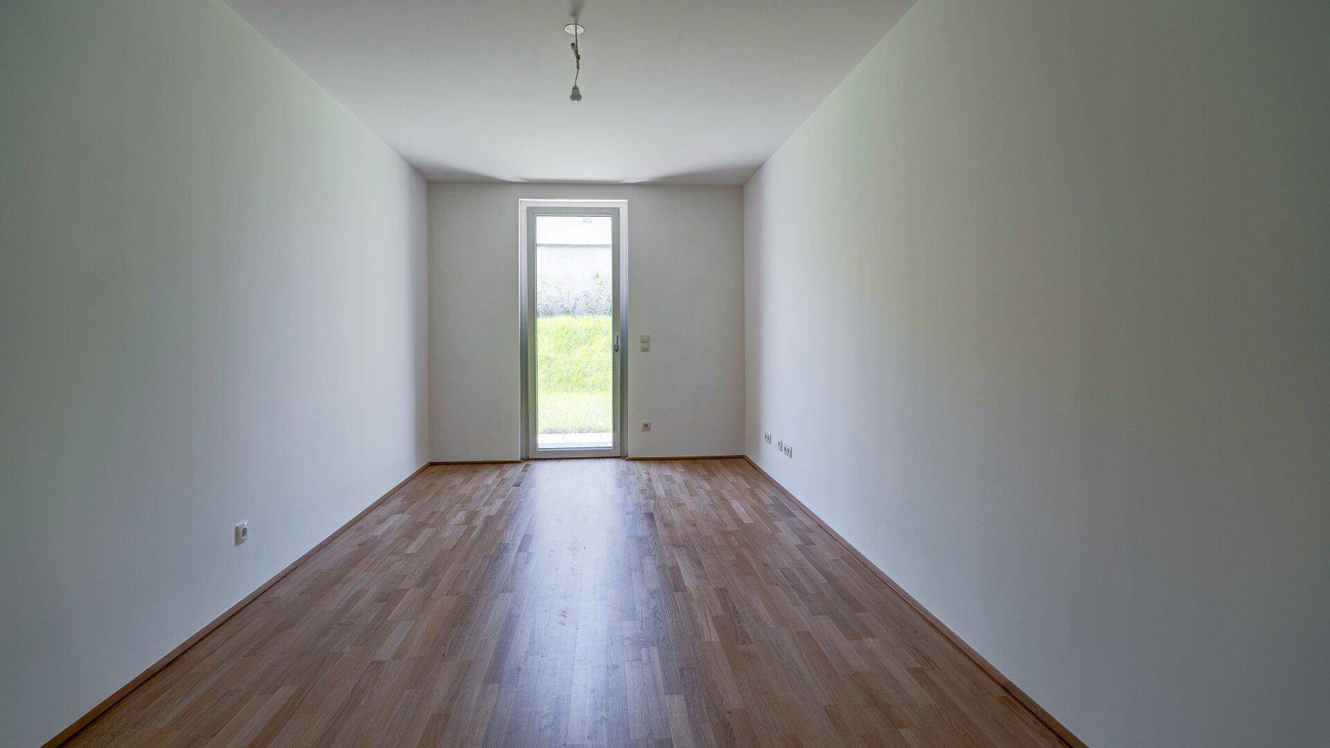 Geräumiges Schlafzimmer mit Holzboden und Zugang zu einem Balkon oder einer Terrasse.