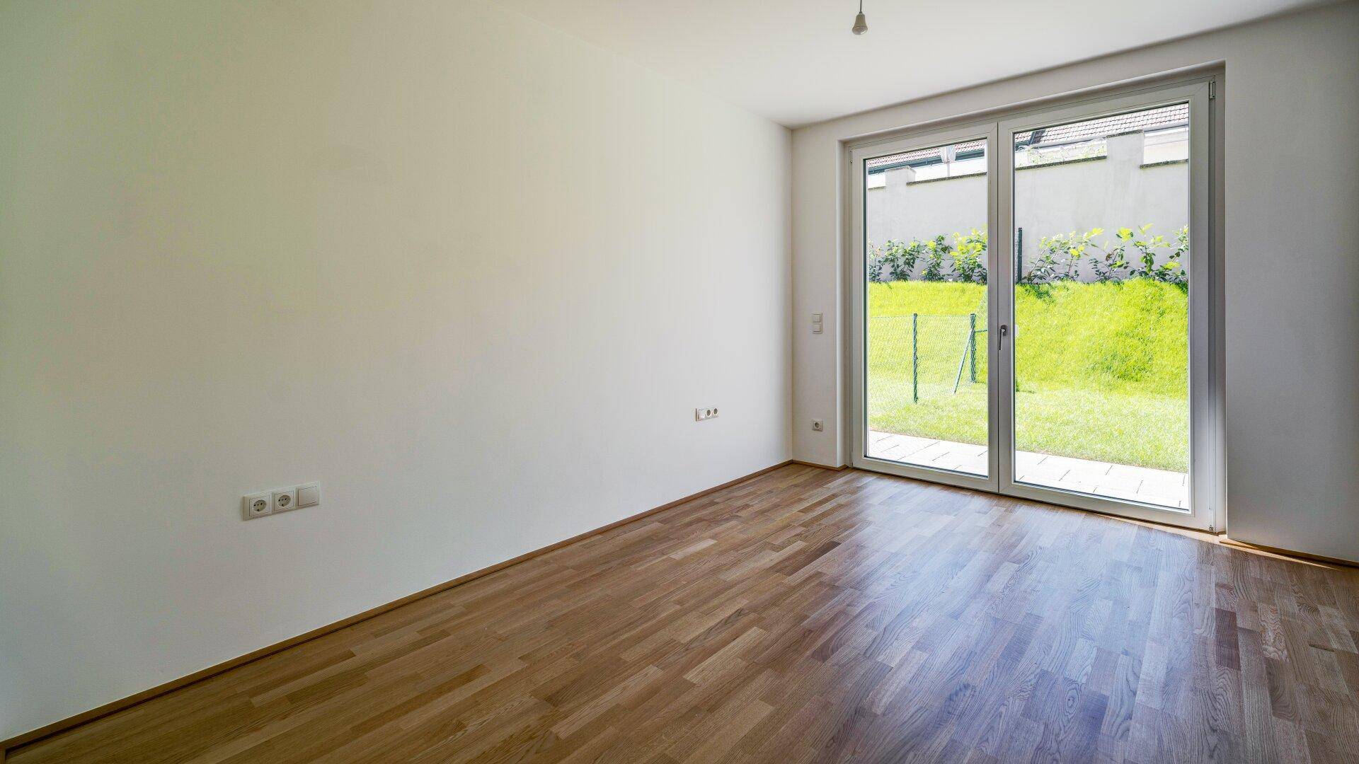 Geräumiger, heller Wohnbereich mit Holzboden und großen Fenstern zum Garten.