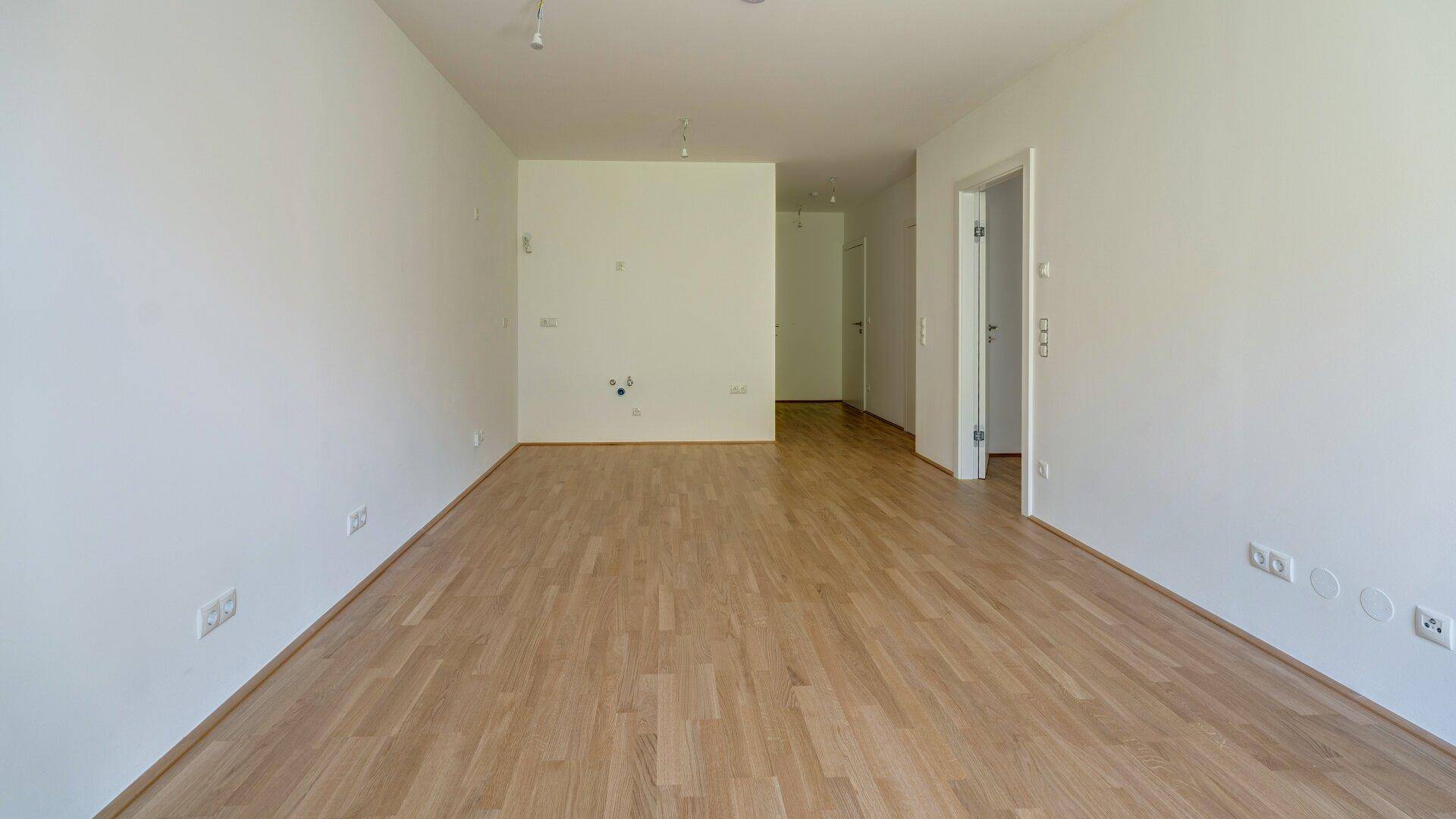 Geräumiger, heller Raum mit Holzboden und weißen Wänden, bereit für individuelle Gestaltung.