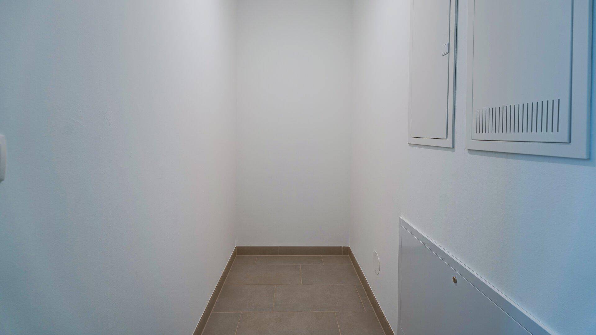 Praktischer Abstellraum mit Fliesenboden und Zugang zu den Versorgungsleitungen, gut organisiert.