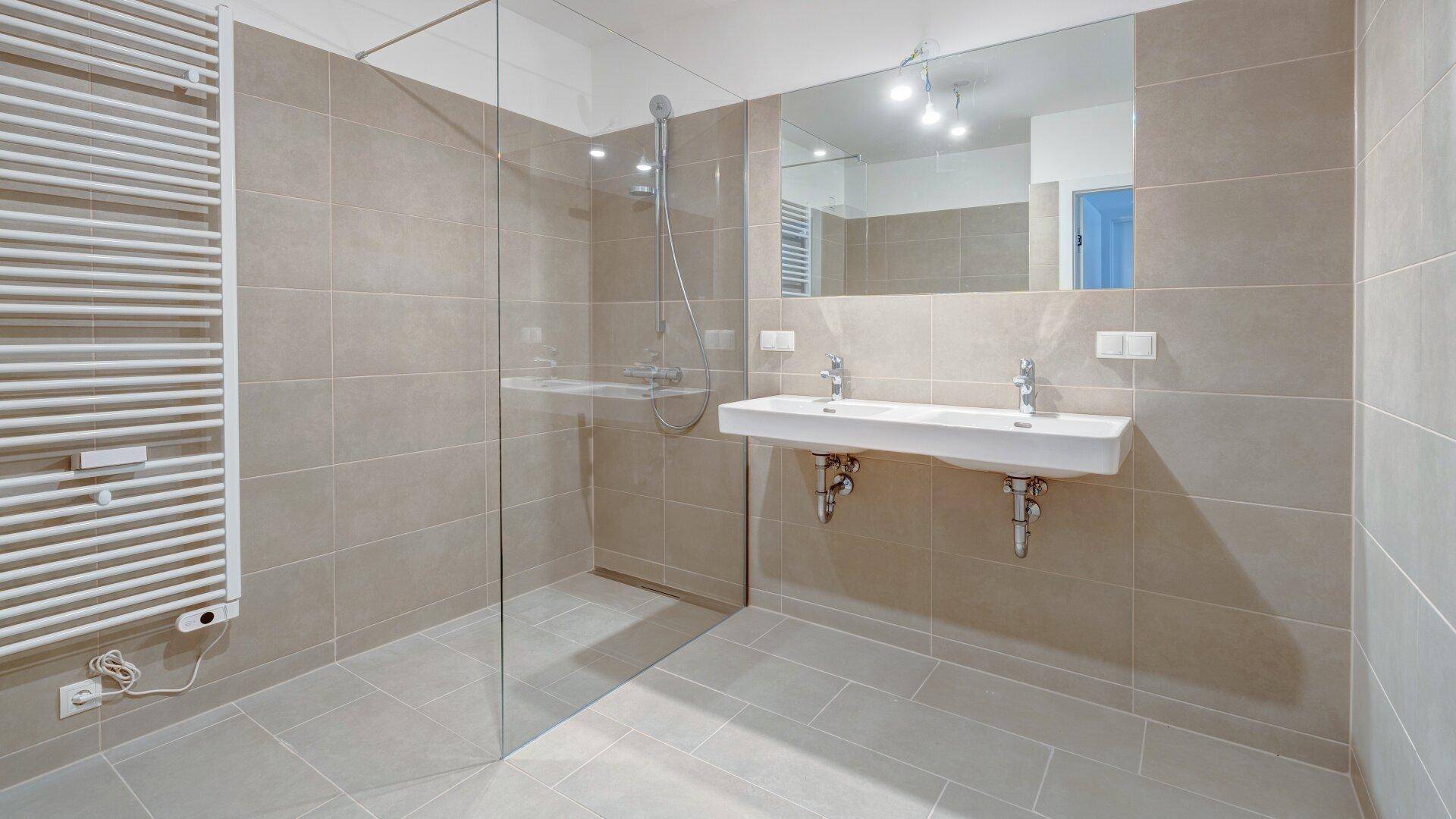 Modernes Badezimmer mit beigefarbenen Fliesen, Doppelwaschbecken und einer ebenerdigen Dusche.