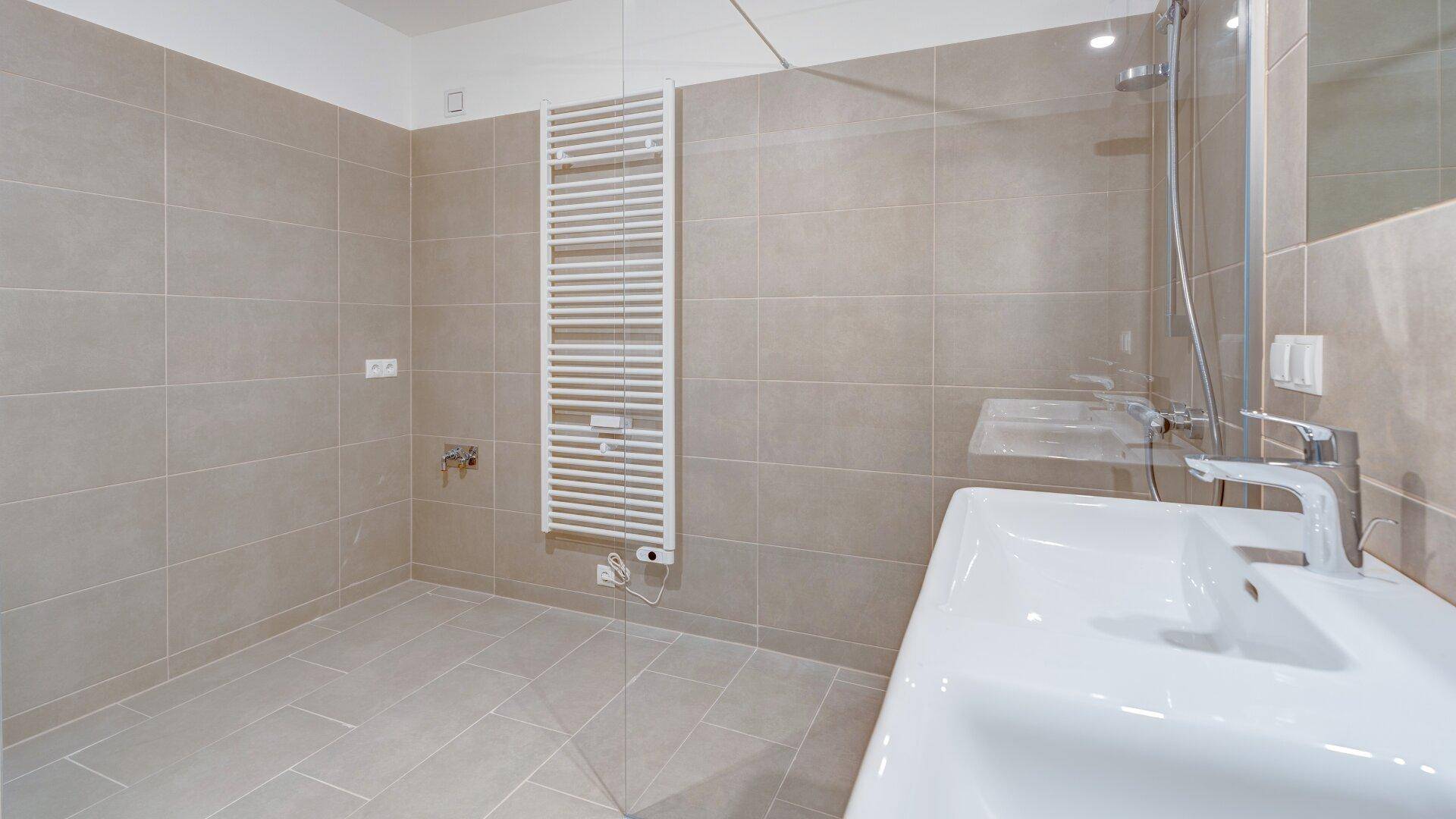 Modernes Badezimmer mit beigefarbenen Fliesen, Einzelwaschbecken und einer ebenerdigen Dusche.