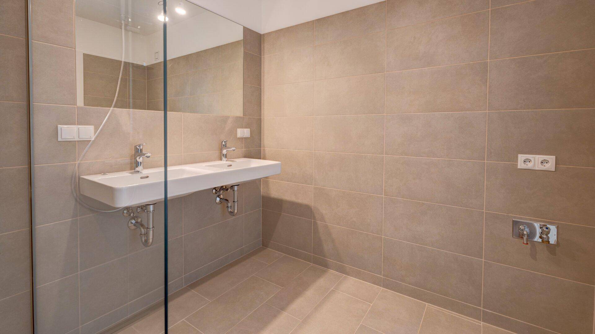 Modernes Badezimmer mit Doppelwaschbecken, großer Spiegelfläche und begehbarer Dusche.