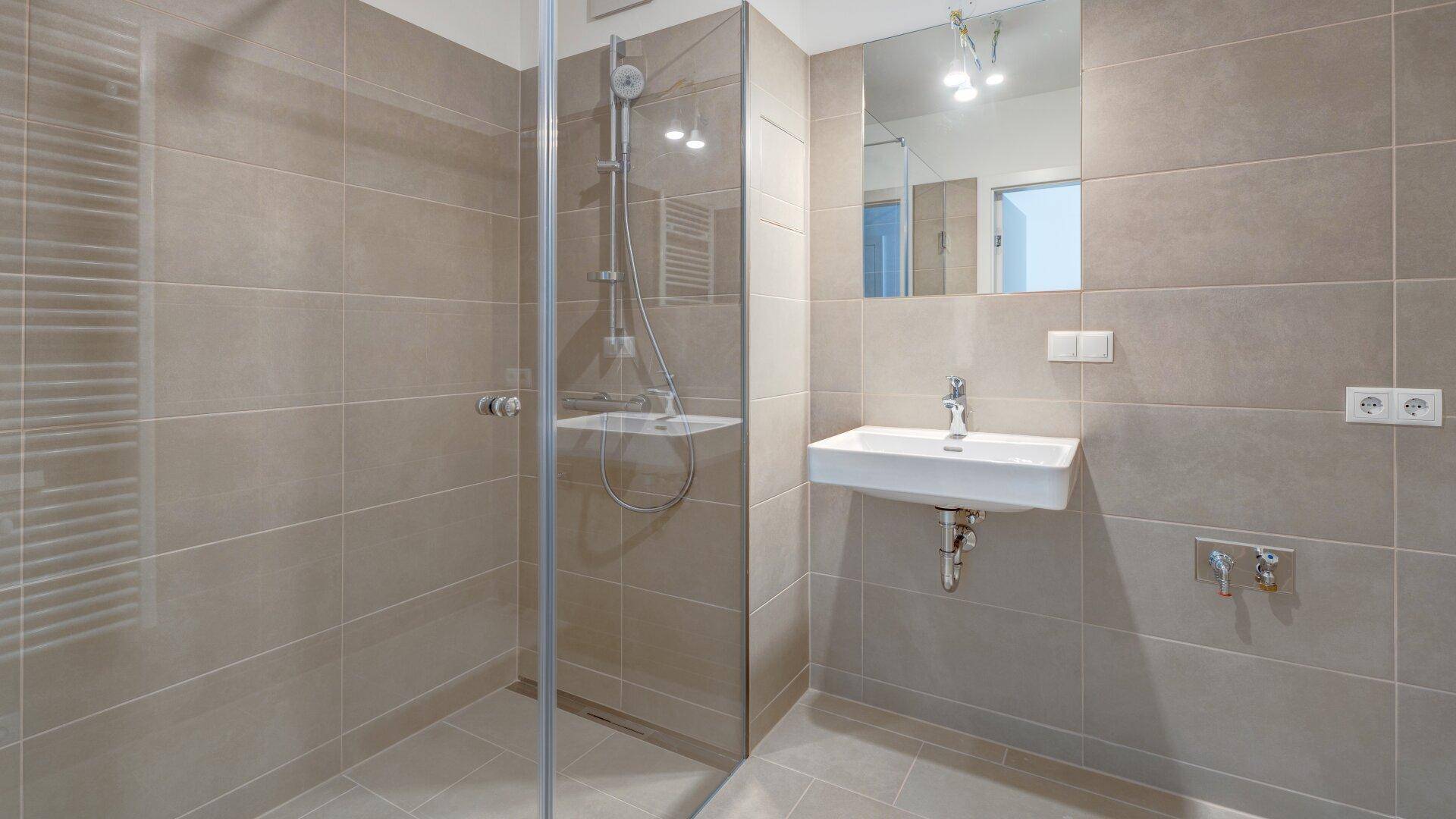 Modernes Badezimmer mit beigefarbenen Fliesen, ebenerdiger Dusche und einem einzelnen Waschbecken.