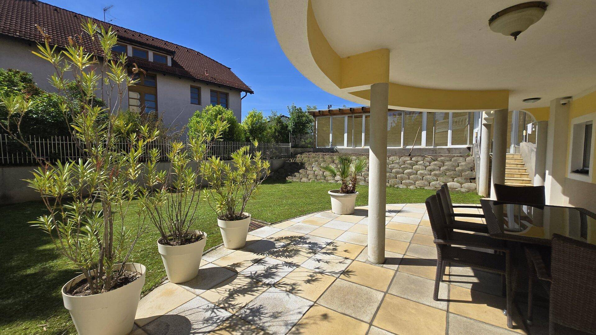 Gemütliche Terrasse mit Sitzgelegenheiten und Blick auf den gepflegten Garten und das Haus.