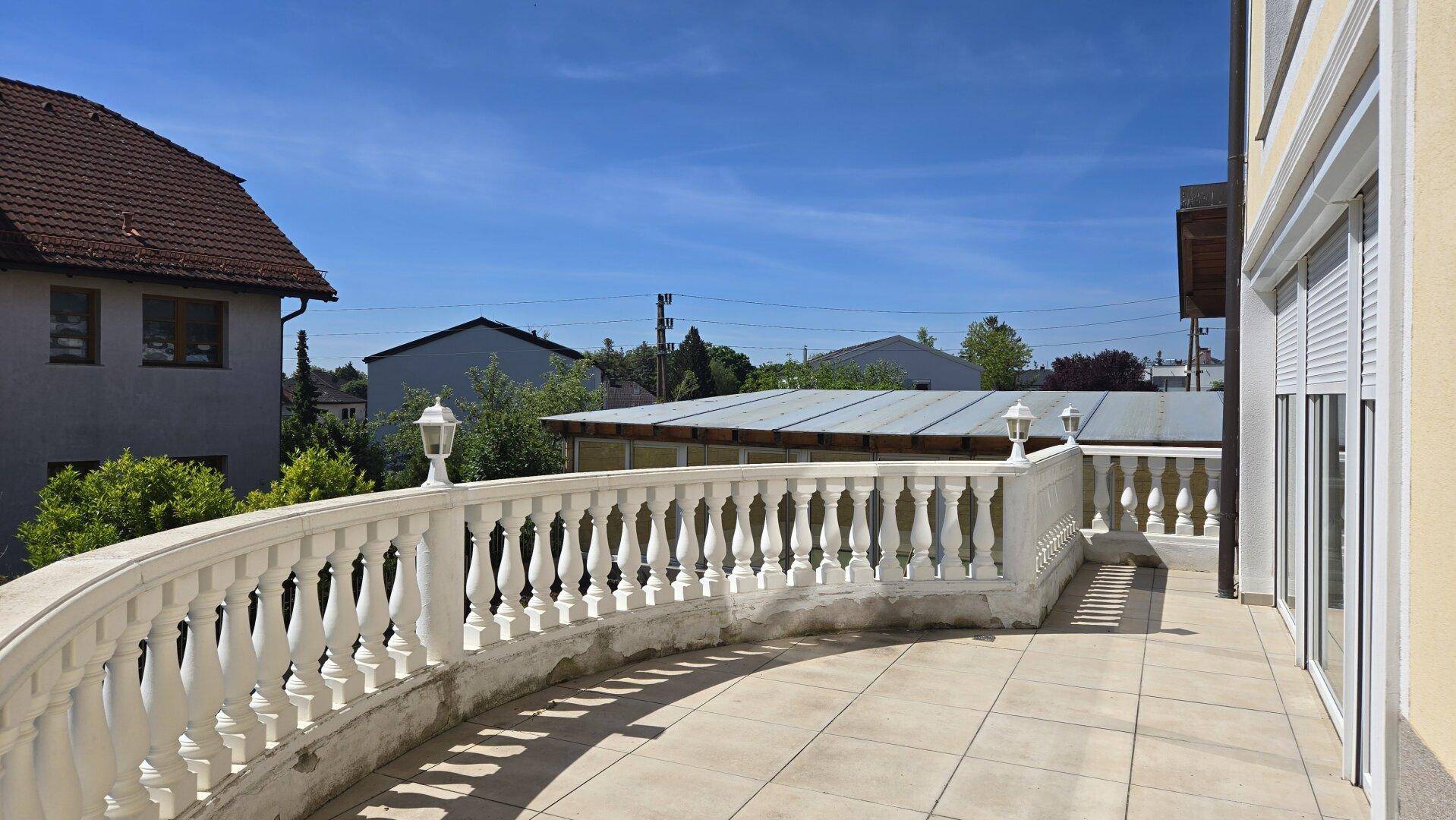 Geräumiger Balkon mit klassischem Geländer und weitem Blick über die Nachbarschaft.