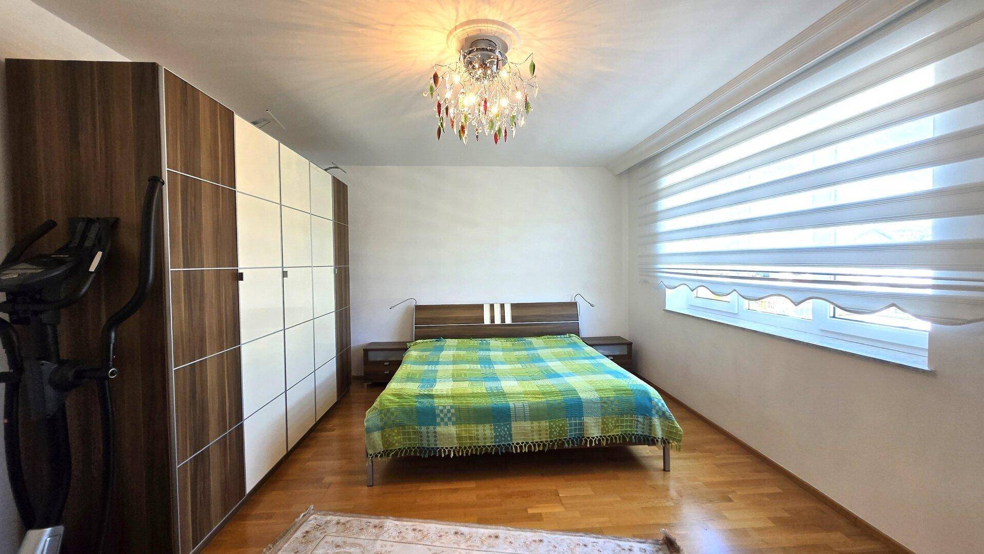 Helles Schlafzimmer mit Doppelbett, großem Kleiderschrank und Holzboden.