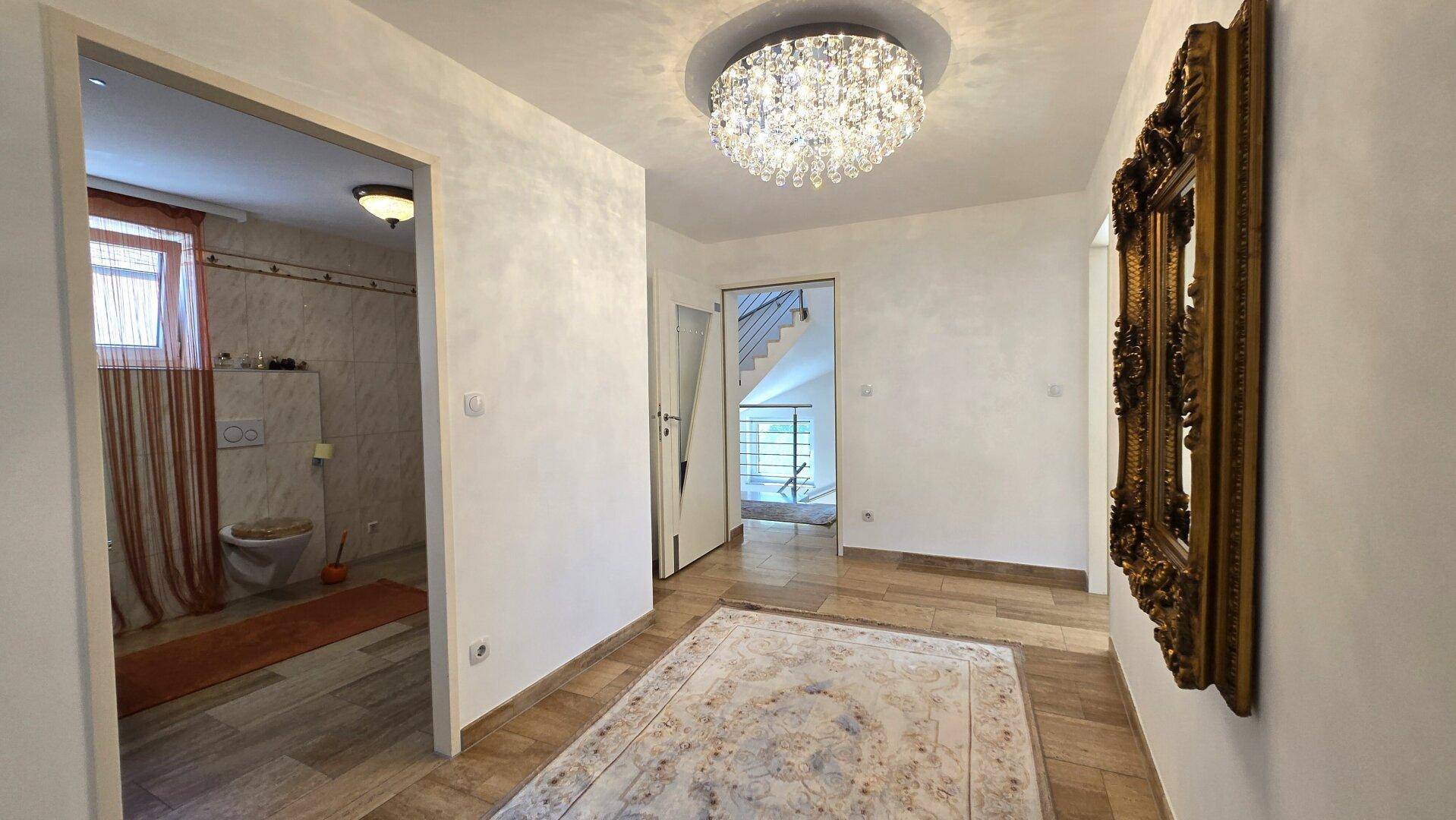 Heller Flur mit Fliesenboden, großem Spiegel und Zugang zu Bad und Treppe.
