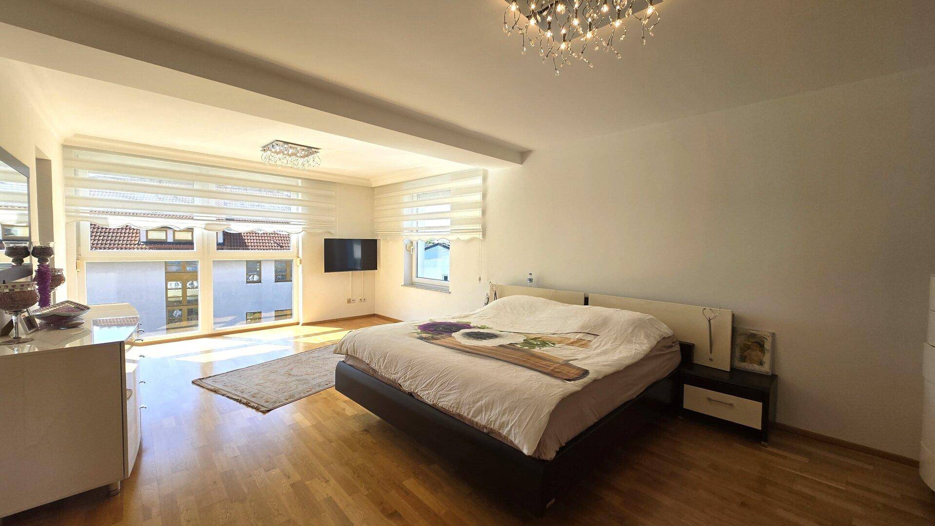 Geräumiges Schlafzimmer mit Doppelbett, Holzboden und großen Fenstern für viel Licht.