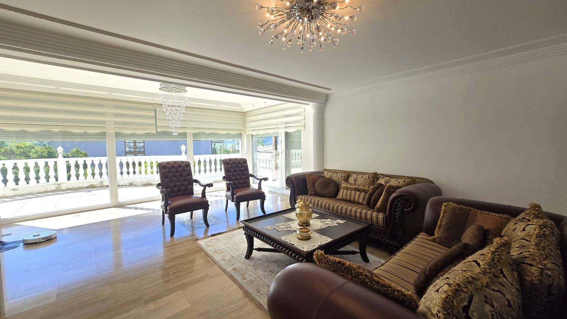 Komfortables Wohnzimmer mit Ledersofas, Couchtisch und großen Fenstern zum Balkon.