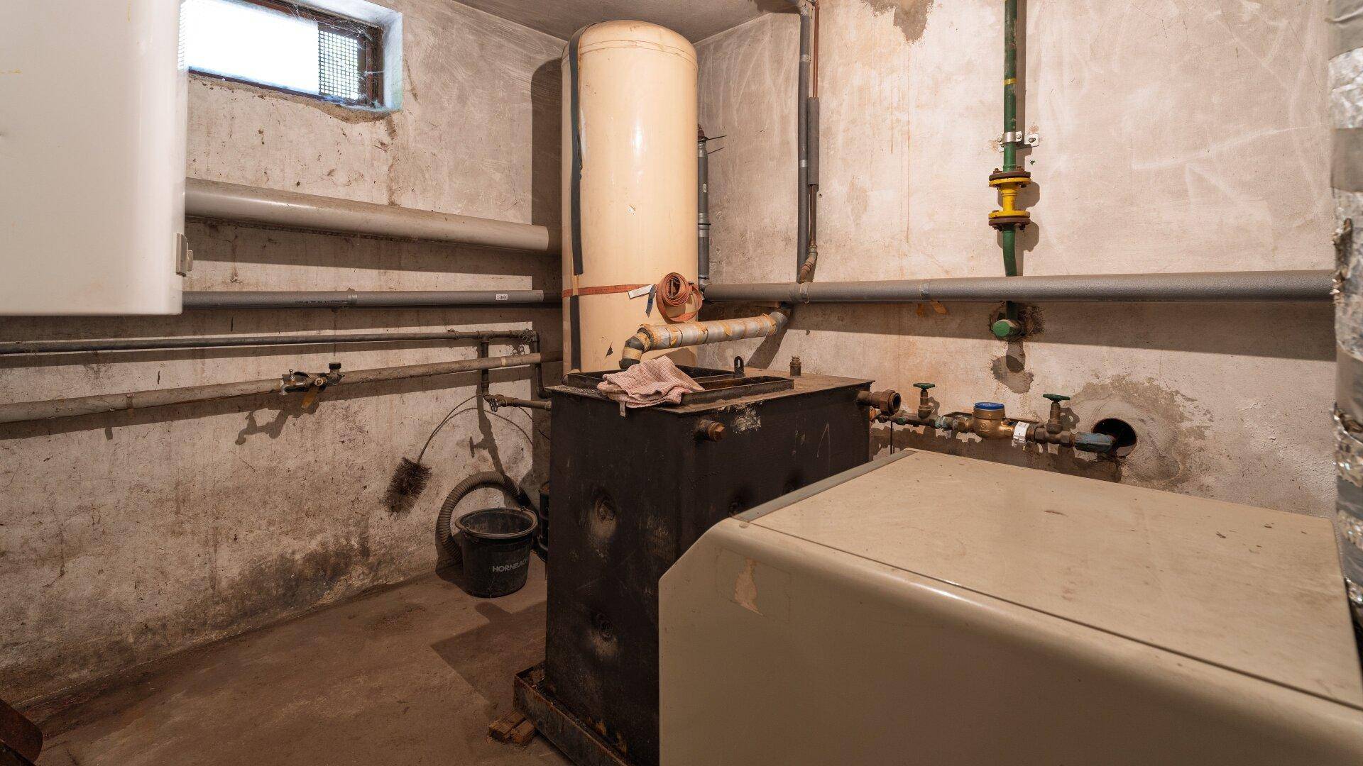 Heizungsraum im Keller mit Warmwasserspeicher und Heizungsanlage, funktional und geräumig.