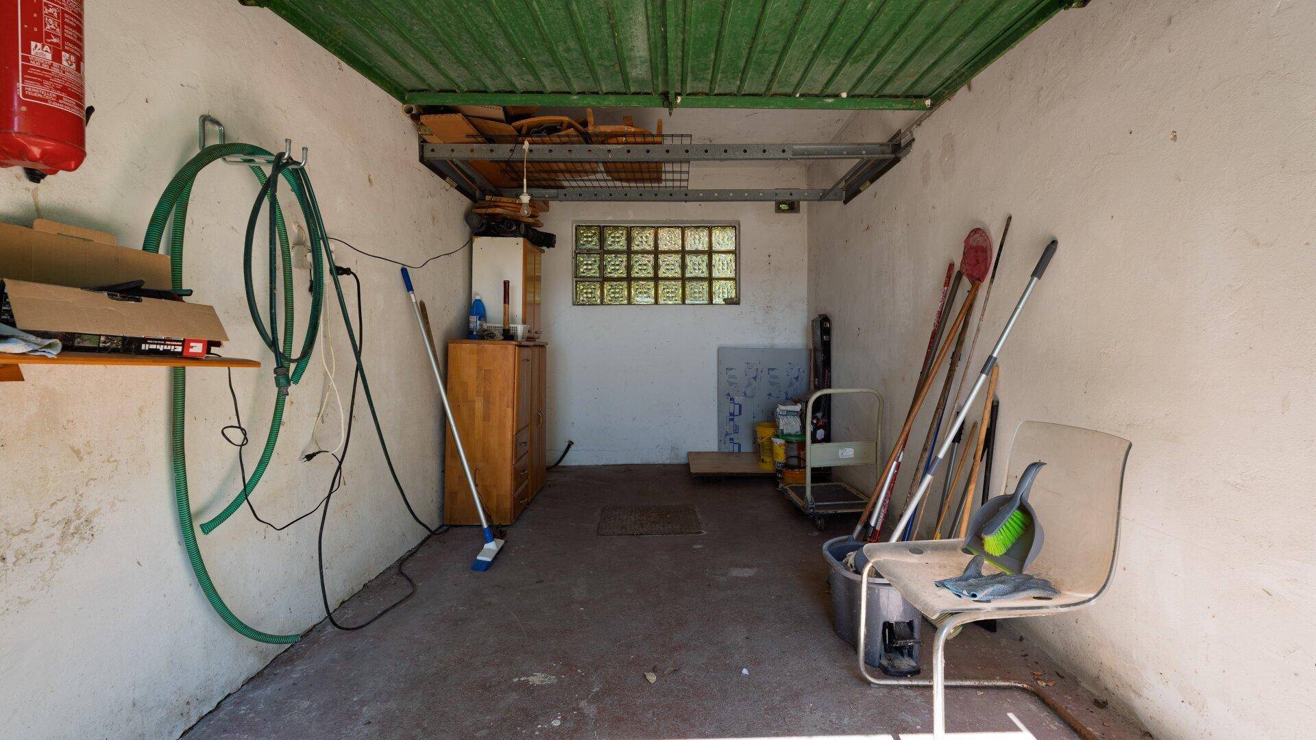 Geräumige Garage mit Stauraum, Werkzeugen und einem Fenster aus Glasbausteinen.