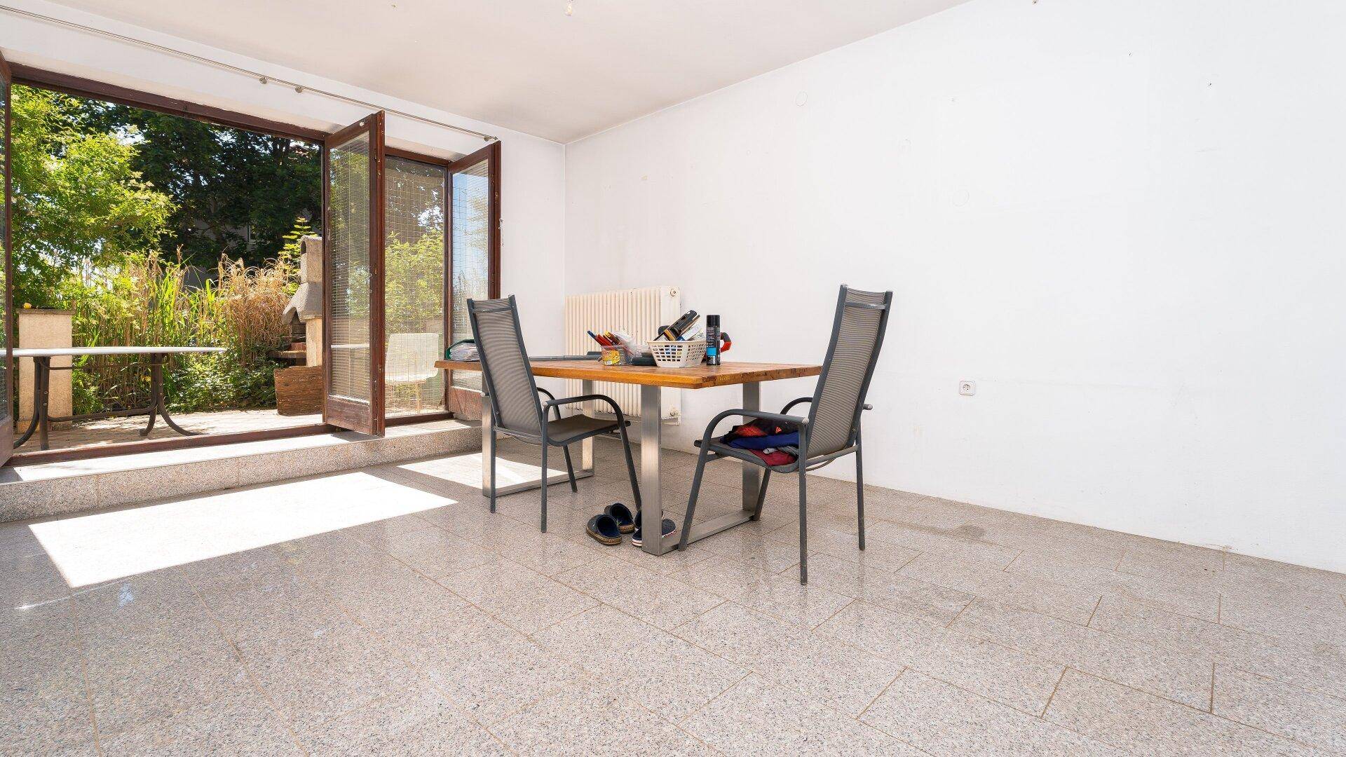 Heller Raum mit Terrassenzugang und einem Tisch mit Stühlen, ideal für gesellige Stunden.