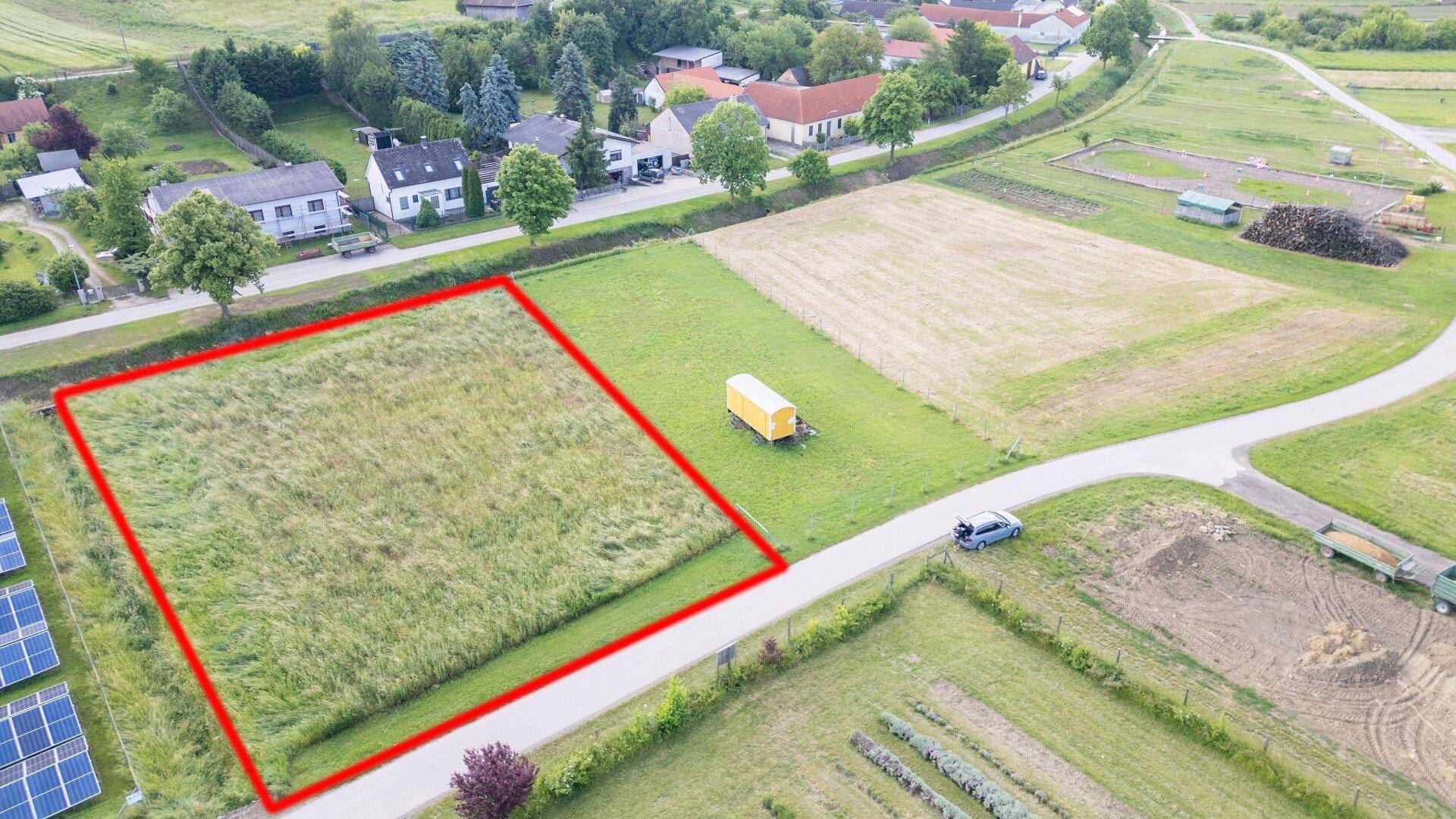 Weitwinkel-Luftaufnahme eines Baugrundstücks mit Solaranlage, Straße und angrenzenden Feldern.