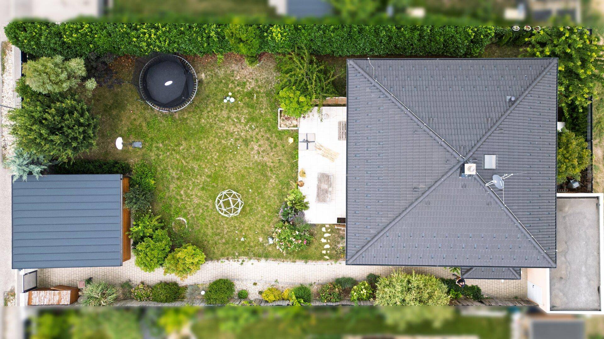 Luftaufnahme des Hauses mit großem Garten, Trampolin und Terrasse.