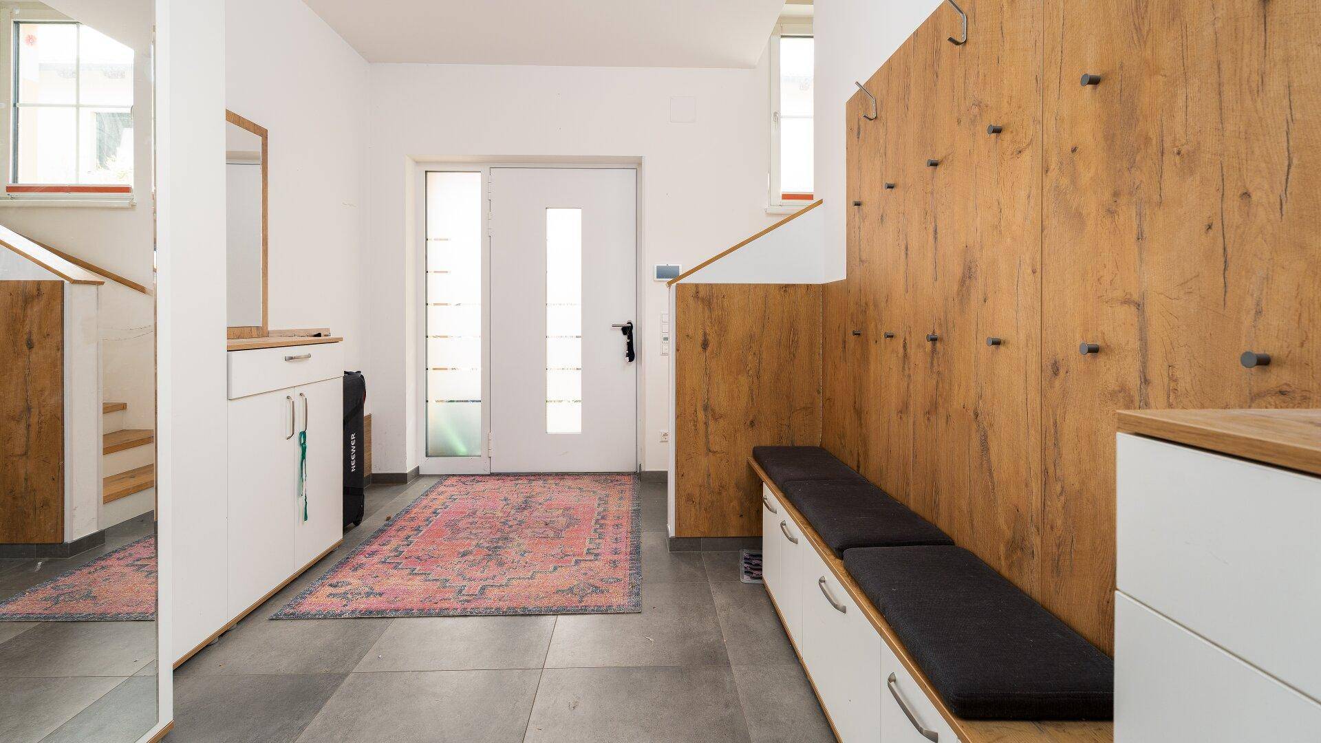 Heller Eingangsbereich mit Garderobe, Sitzbank und Holzvertäfelung.