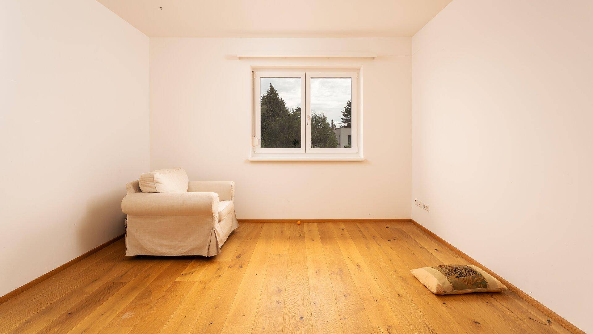 Geräumiges Zimmer mit Holzboden und großem Fenster, ideal als Schlaf- oder Gästezimmer.
