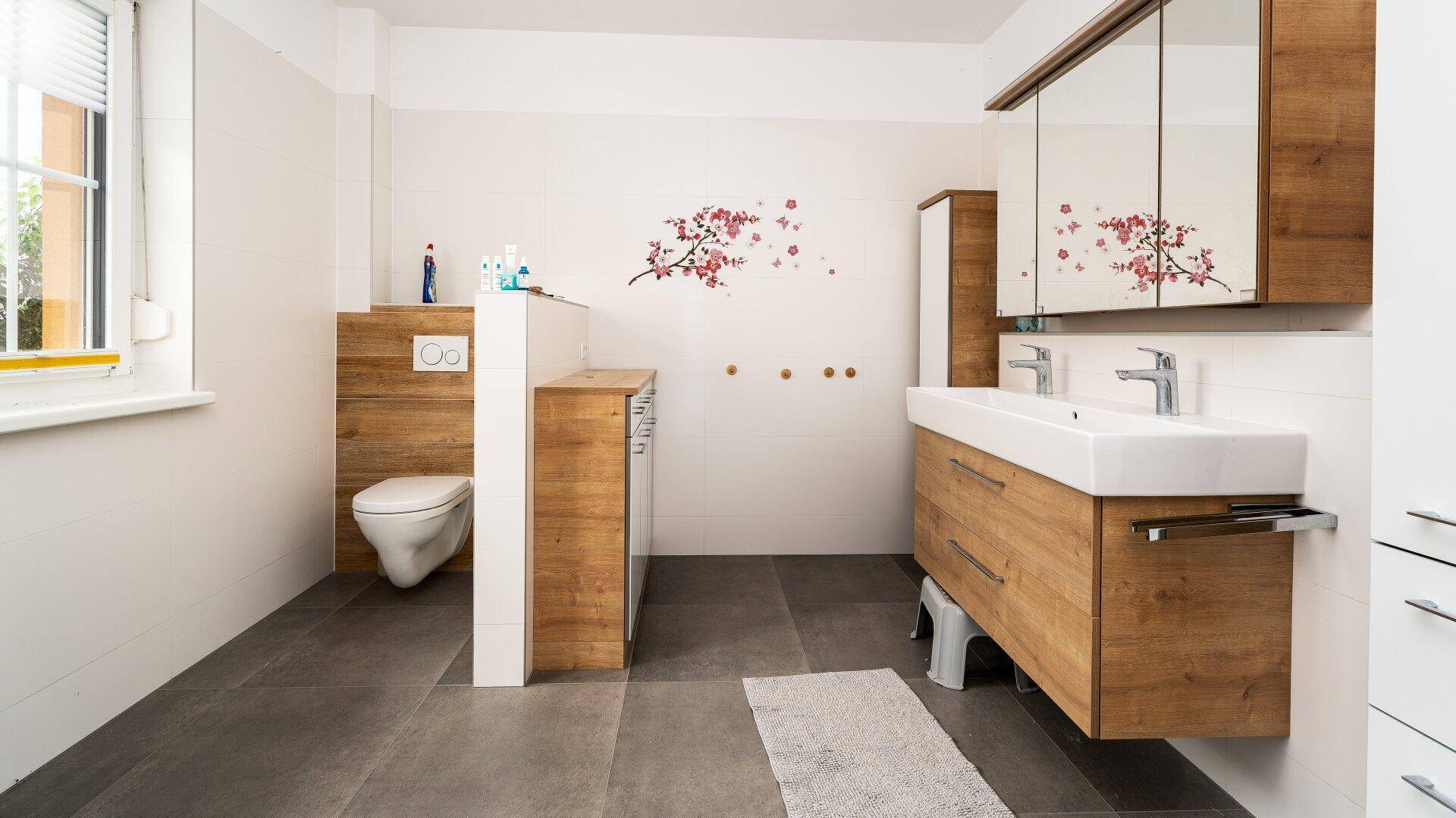 Modernes Badezimmer mit Doppelwaschbecken, Spiegelschrank und Holzelementen.