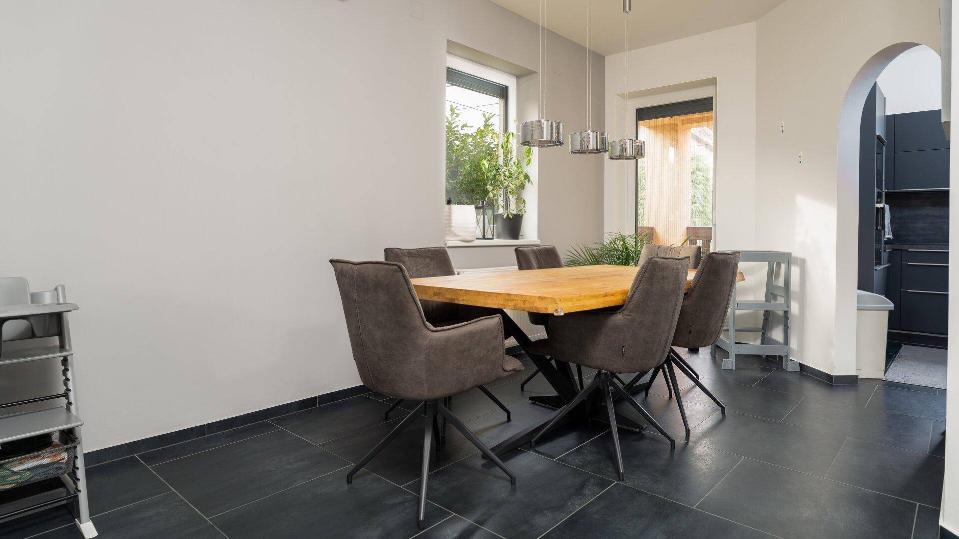 Essbereich mit Holztisch und modernen Hängelampen, offen zum Küchenbereich.