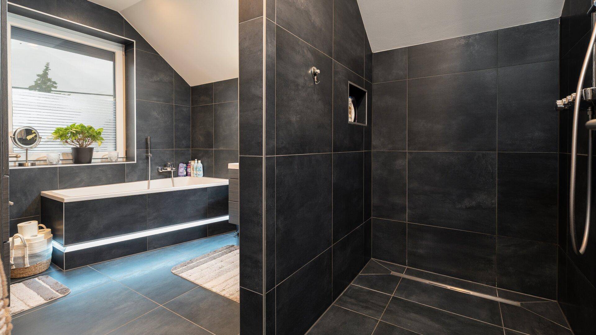 Modernes Badezimmer mit dunklen Fliesen, Badewanne und begehbarer Dusche.
